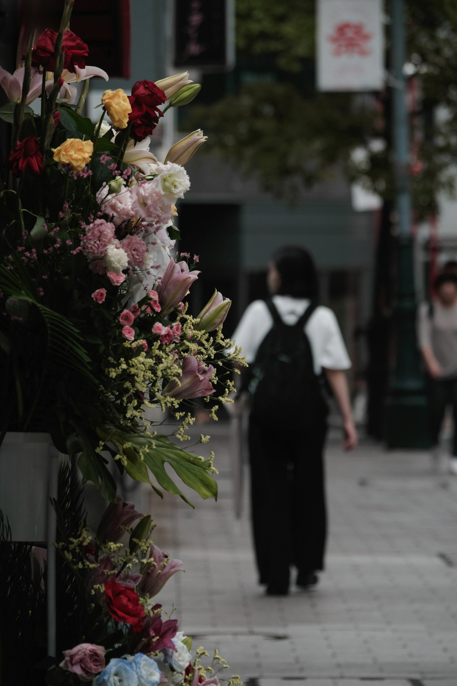 Person geht an einer Blumenpräsentation auf einer Stadtstraße vorbei