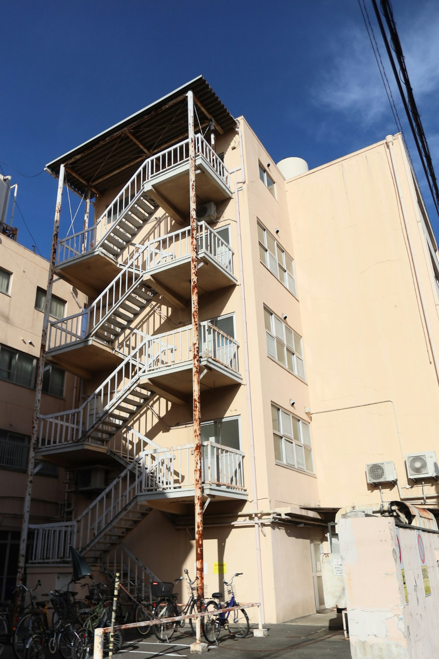 Esterno di un edificio rosa con una scala in metallo bianco