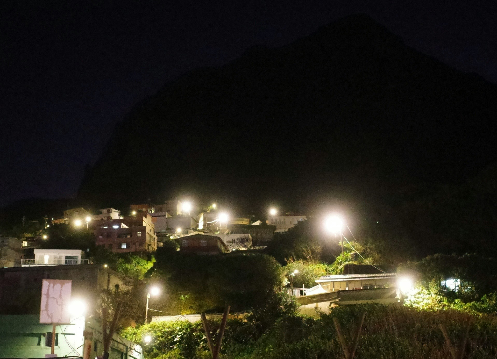 夜の住宅街の街灯と建物のある丘の風景
