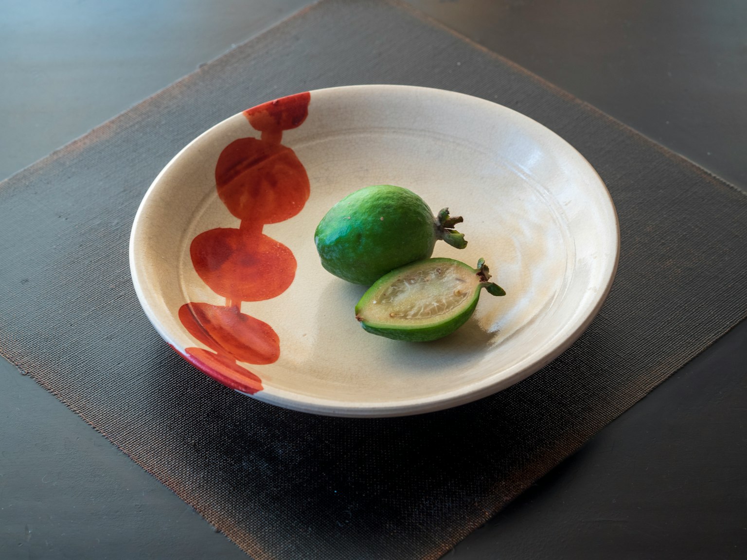 Une assiette blanche avec un fruit vert et un fruit tranché dessus