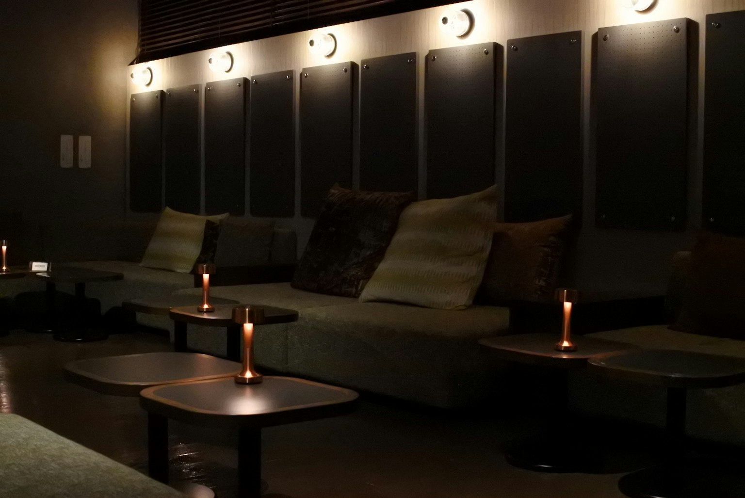 Área de salón acogedora con sofás y mesas iluminadas por luces suaves y velas