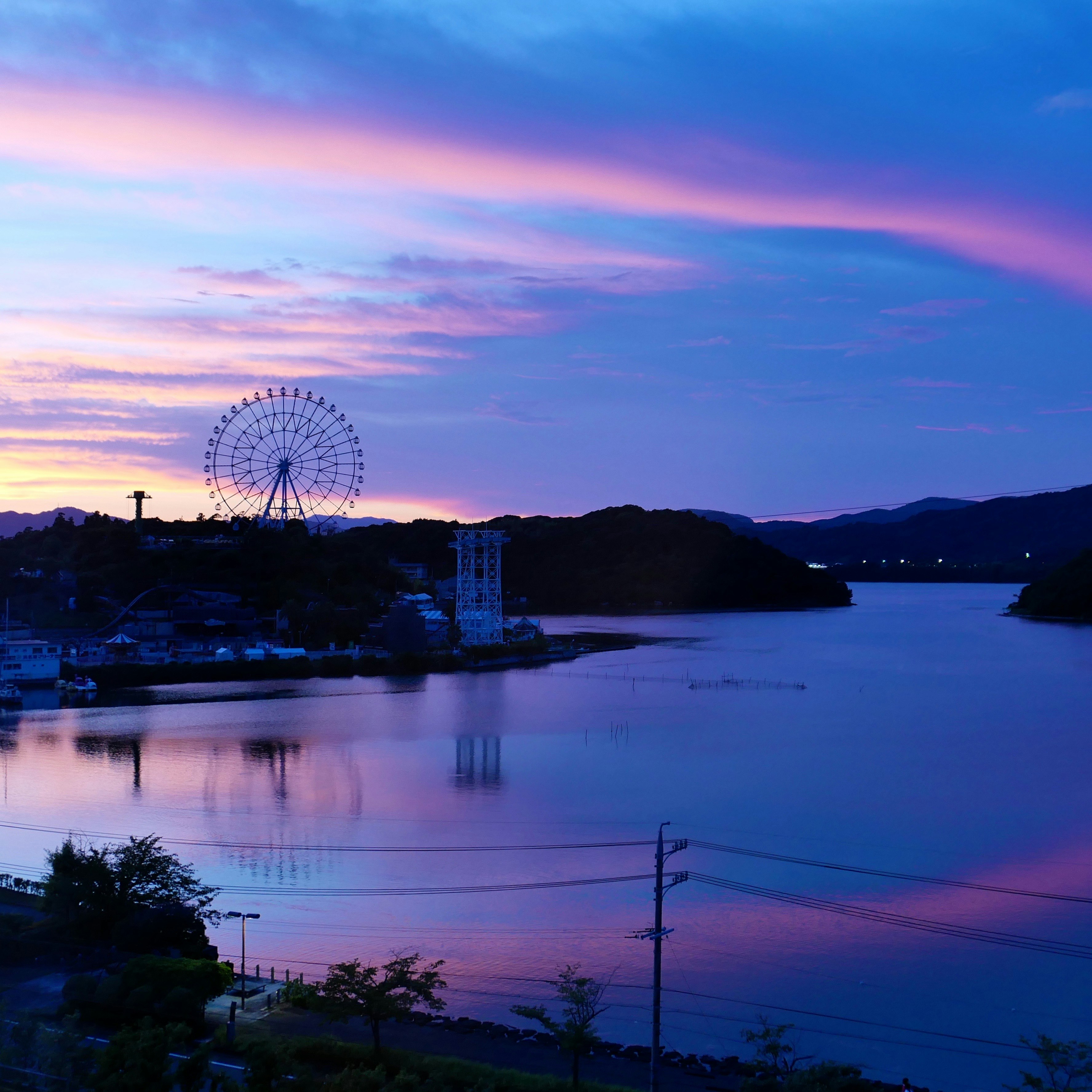 夕焼けとブルーアワーの湖畔に浮かぶ観覧車のシルエット