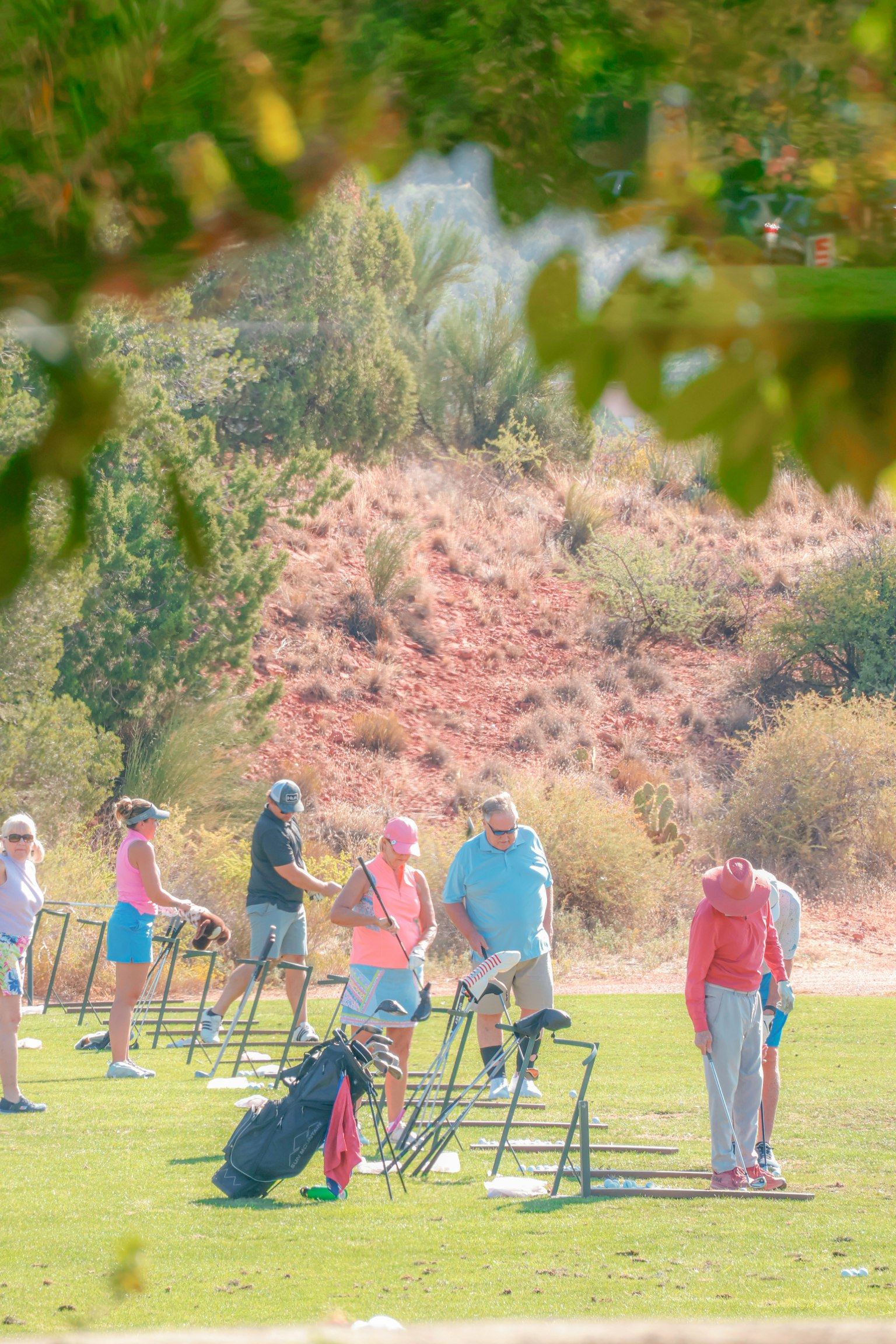 Group of people practicing at a golf driving range wearing colorful outfits and holding golf clubs