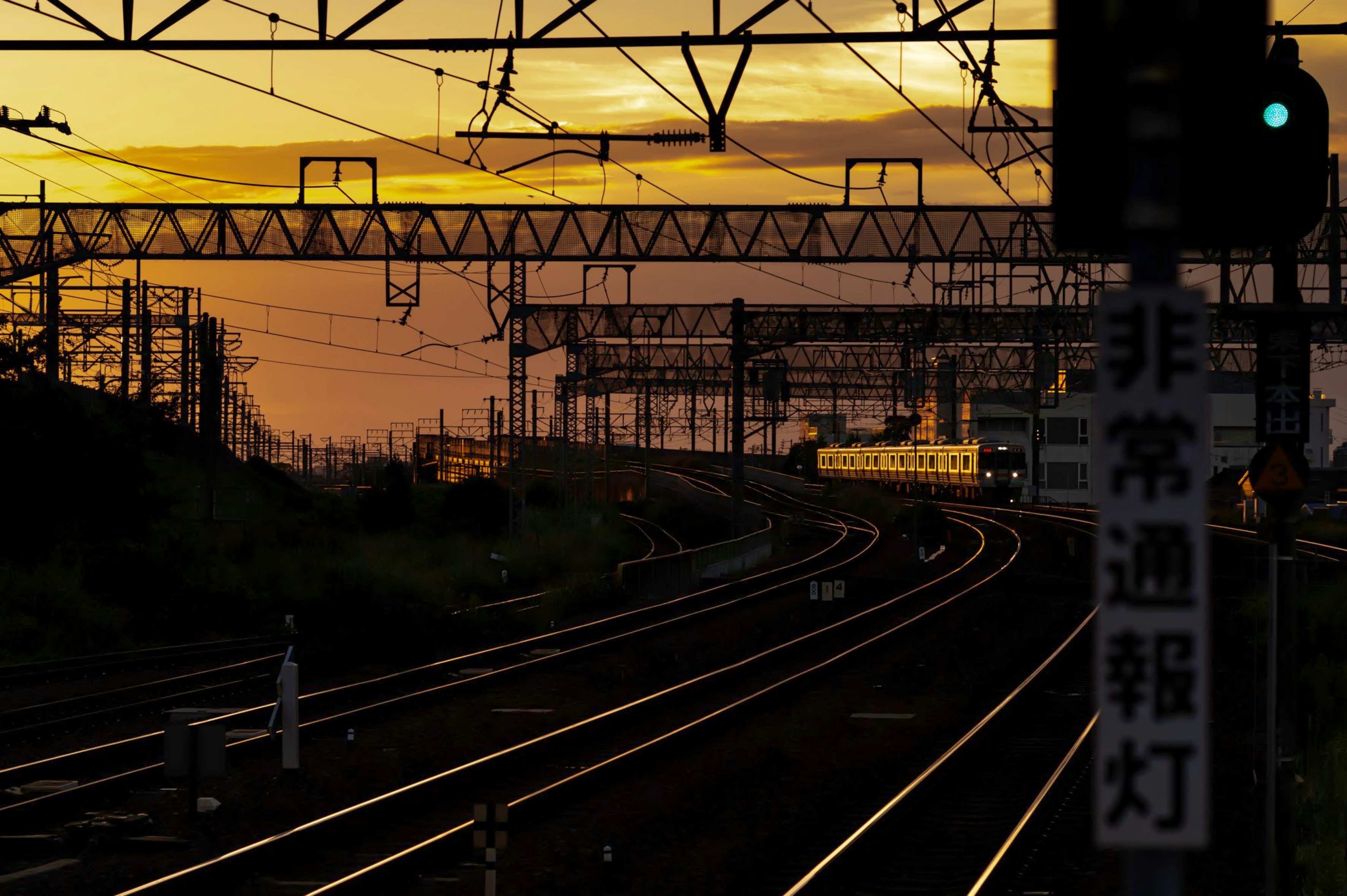 夕焼けのホームから見える線路と列車の走行