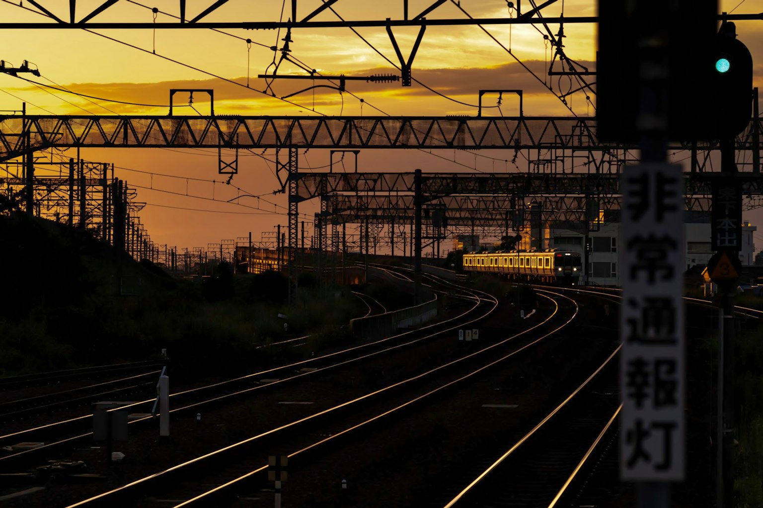 ทิวทัศน์ทางรถไฟที่มีแสงอาทิตย์ตกและสัญญาณไฟ