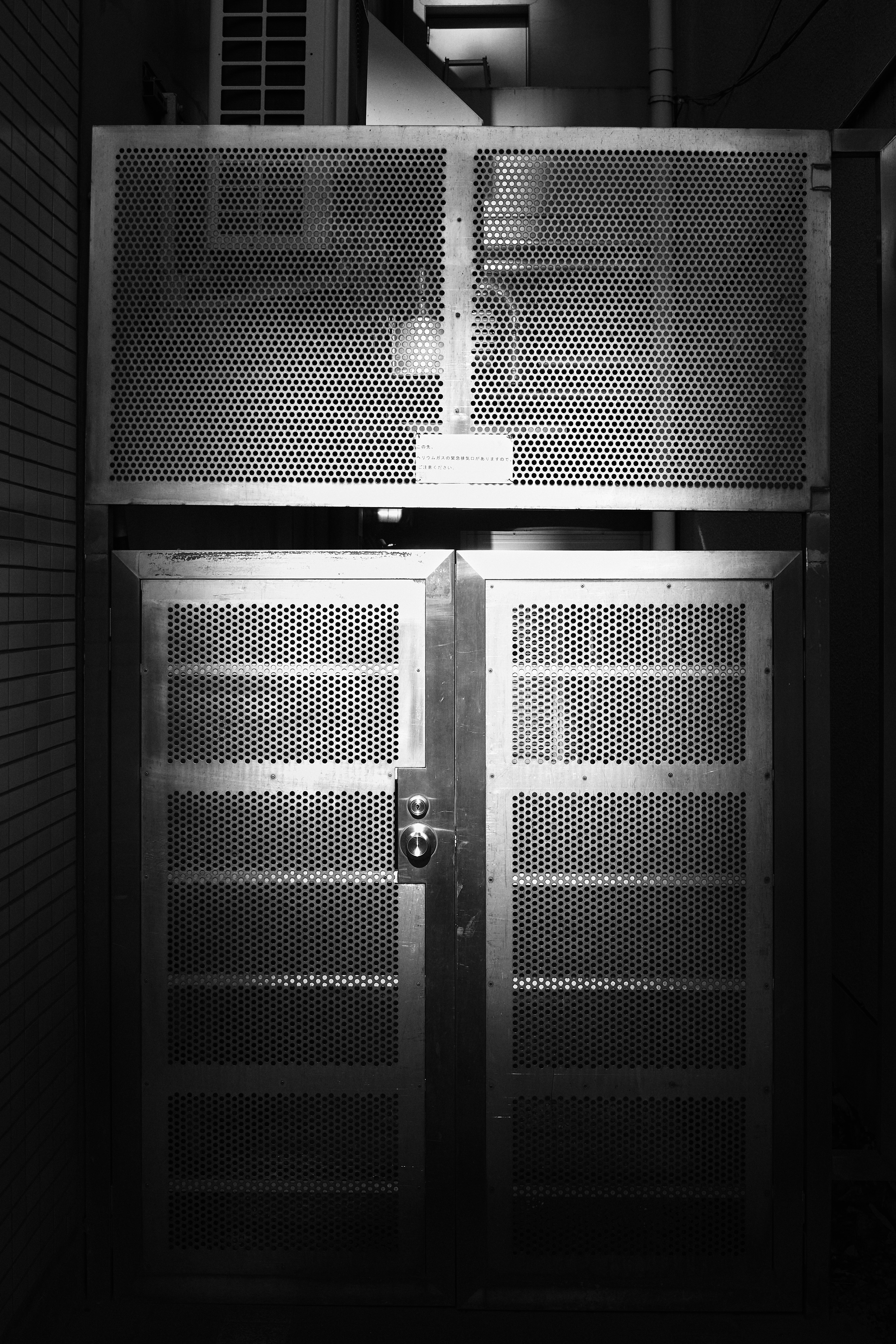 dim indoor corridor with a metal lattice door and wall panels