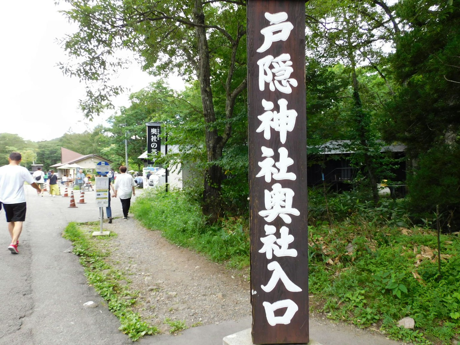 Schild, das den Eingang zum Togakushi-Schrein mit üppigem Grün in der Umgebung anzeigt