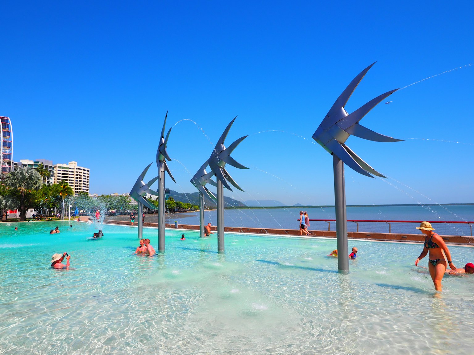 Sculture artistiche di pesci spruzzanti in una piscina sotto un cielo blu chiaro
