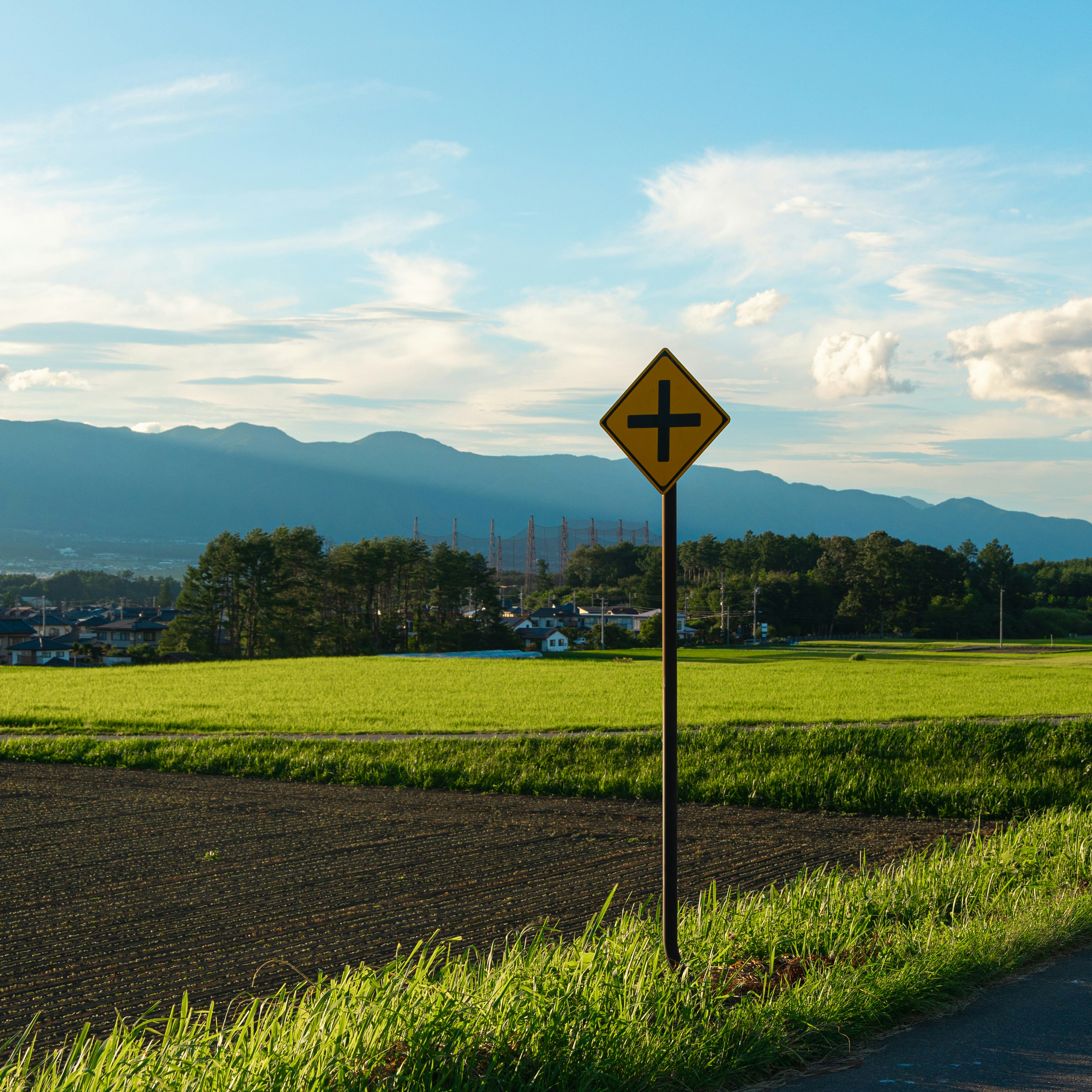 田園風景の道端にある十字架標識のある風景