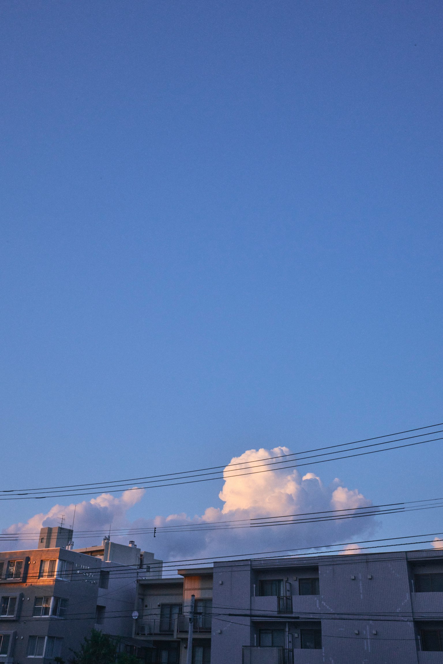 Heller blauer Himmel mit flauschigen weißen Wolken über städtischen Gebäuden