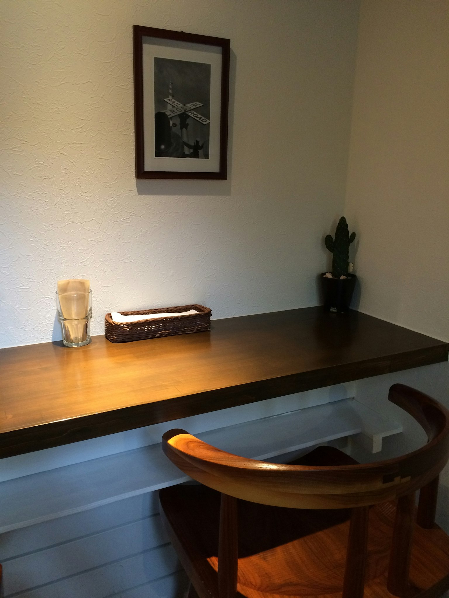 Ein ruhiger Arbeitsbereich mit einem Holztisch und einem Stuhl, eingerahmt von einem Schwarz-Weiß-Bild an der Wand und einer kleinen Topfpflanze