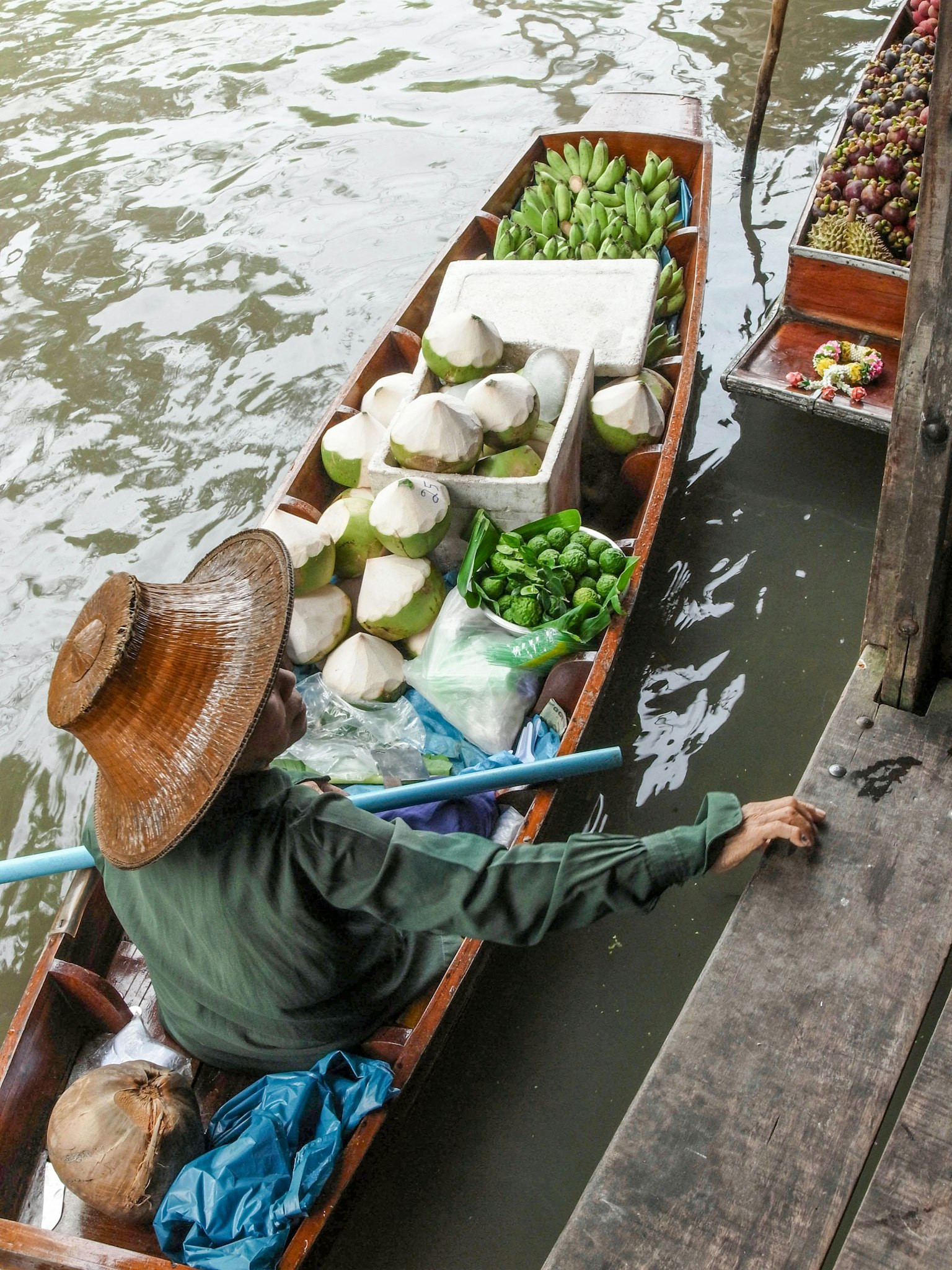 Seorang penjual di perahu yang mengangkut produk segar di sepanjang saluran air