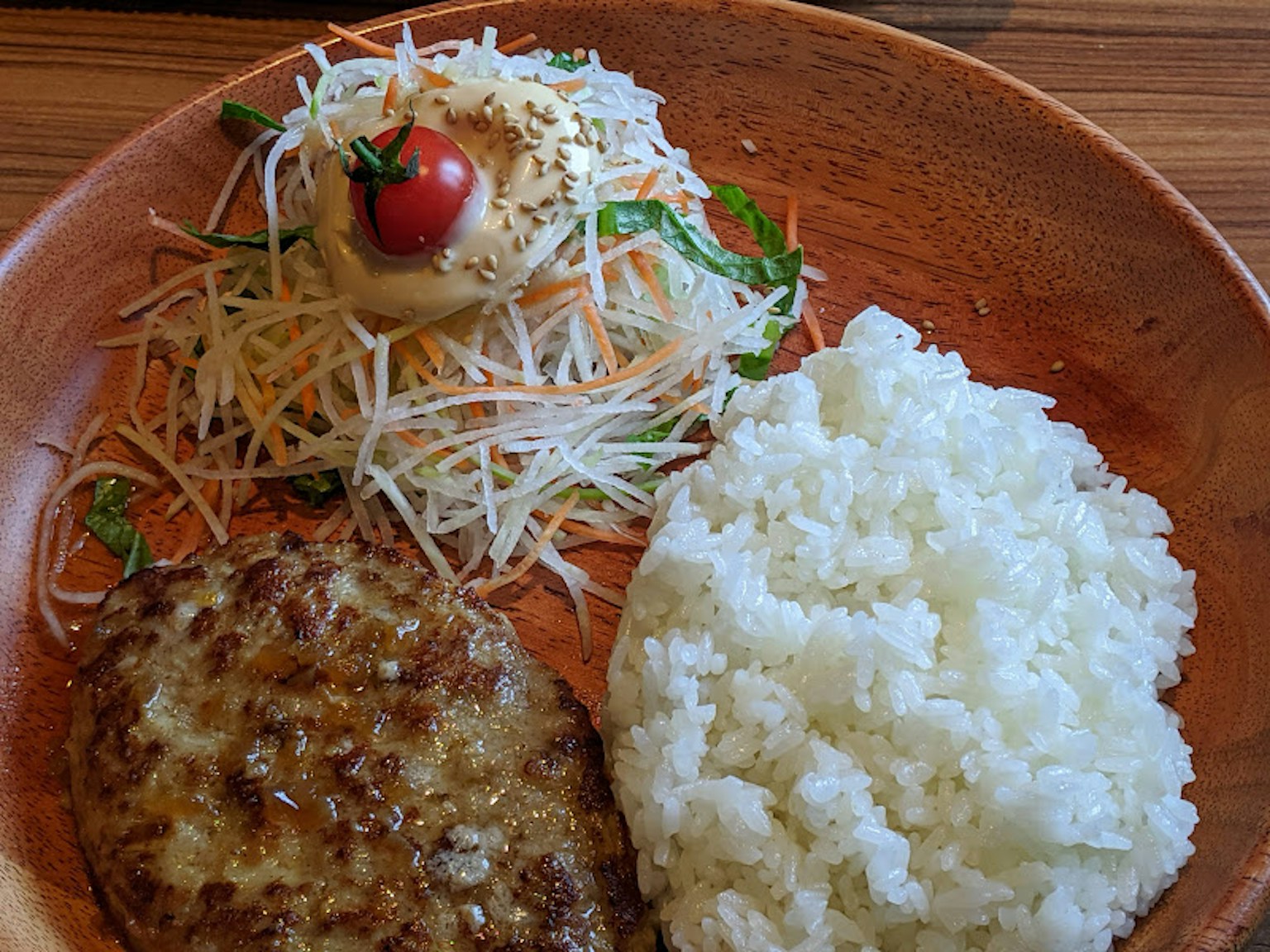 A plate with white rice salad and a meat patty