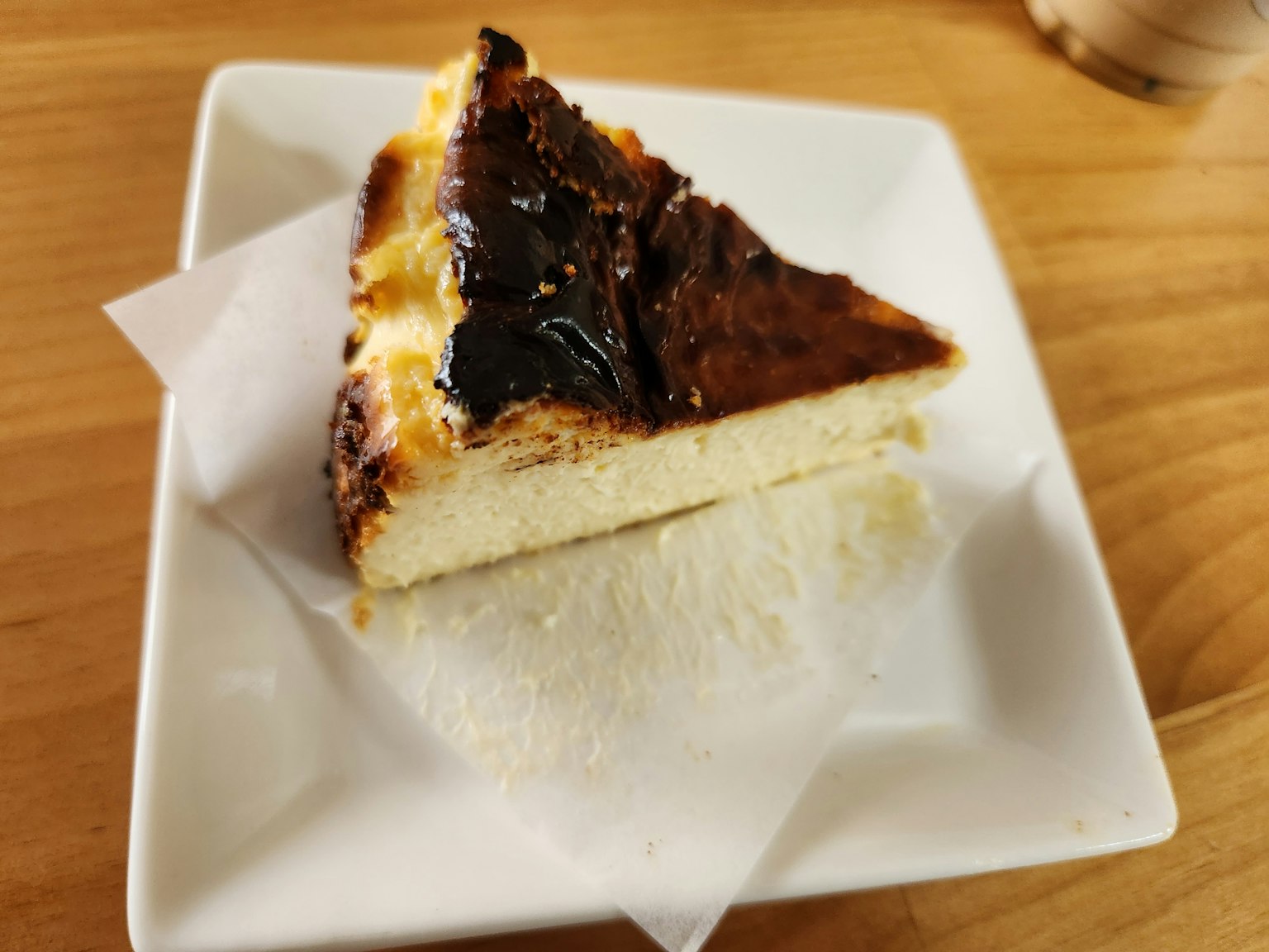 Một miếng bánh cheesecake nướng trên đĩa vuông trắng