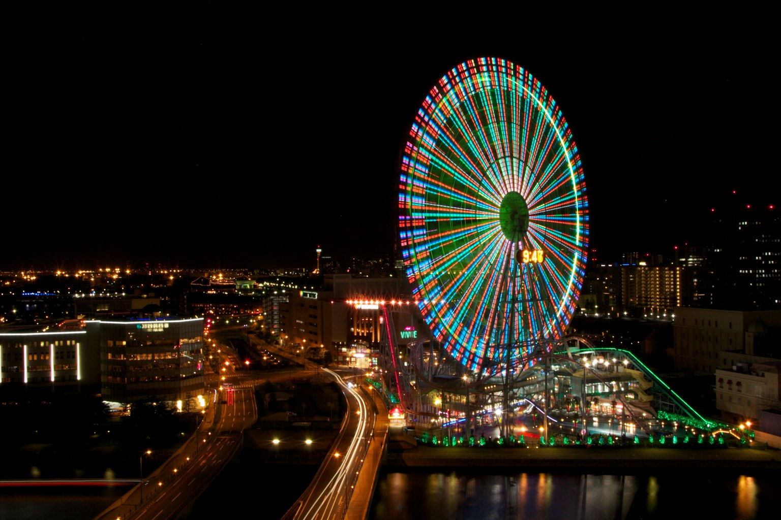 Grande roue colorée illuminée la nuit avec un paysage urbain