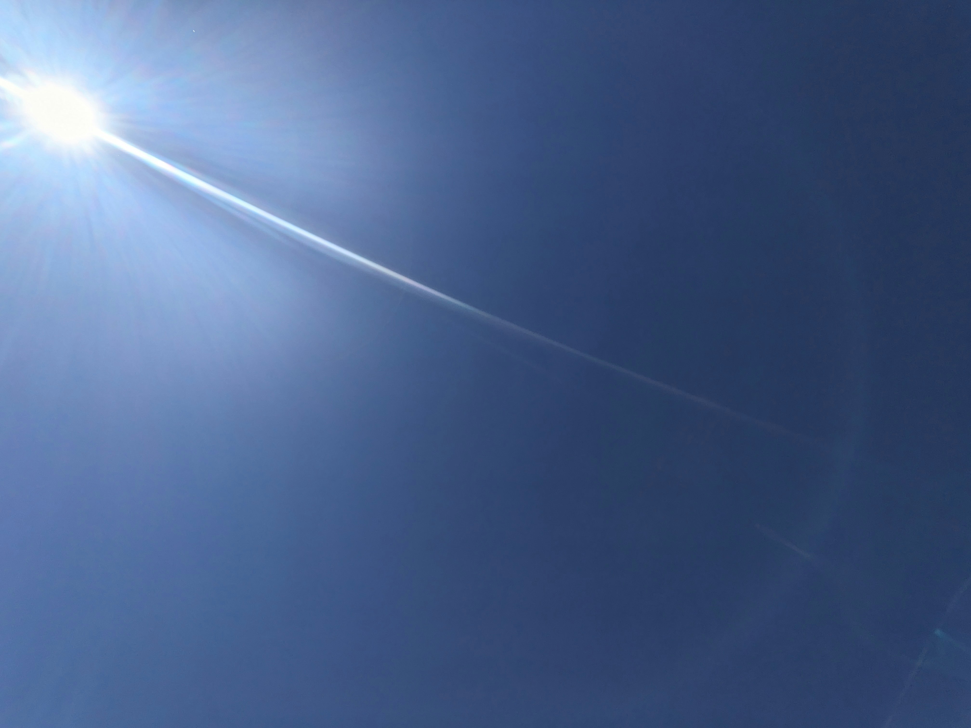 青空に伸びる光の筋が印象的な空の上部