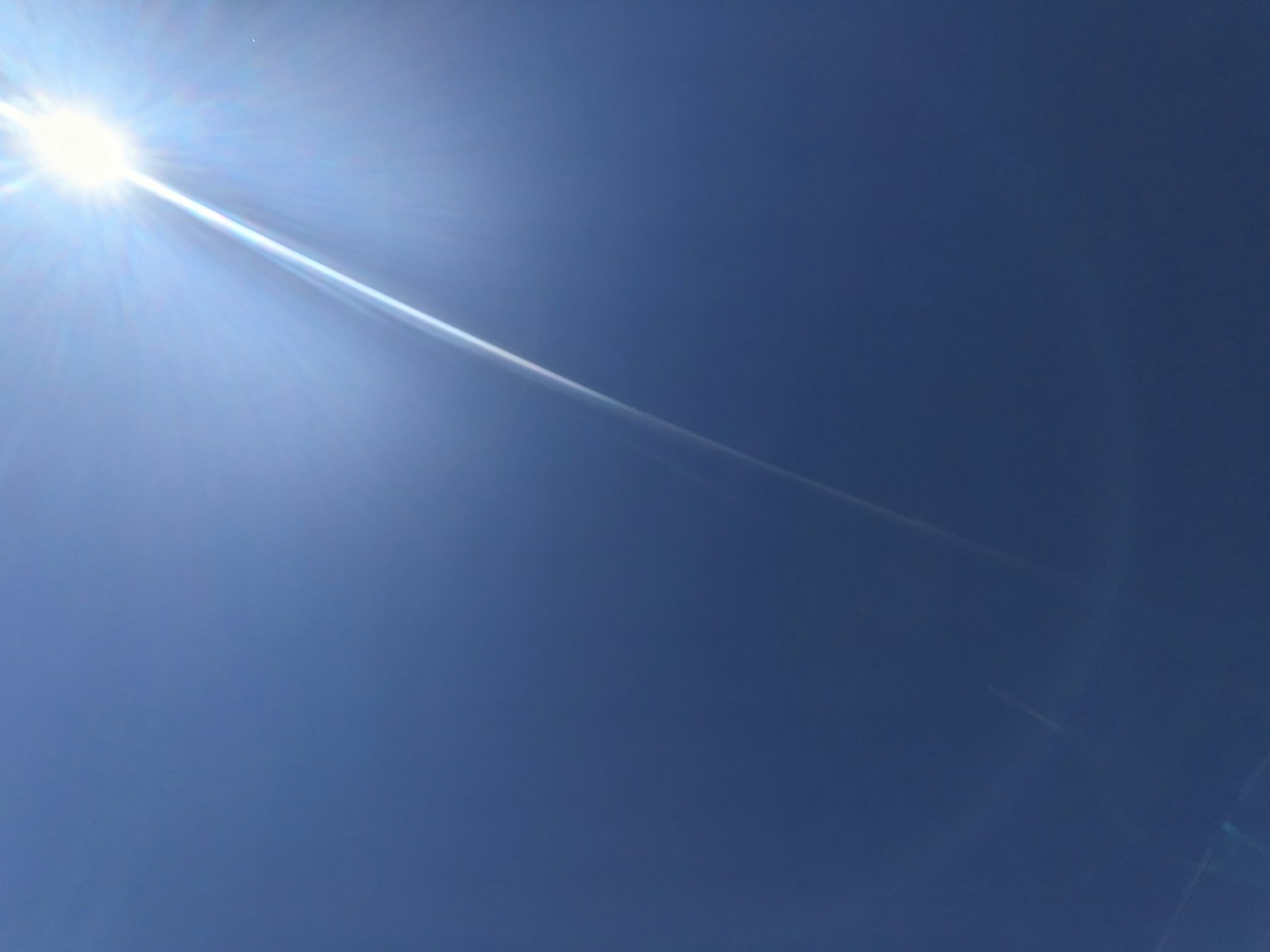 Ciel bleu vif avec soleil et traînée de nuage