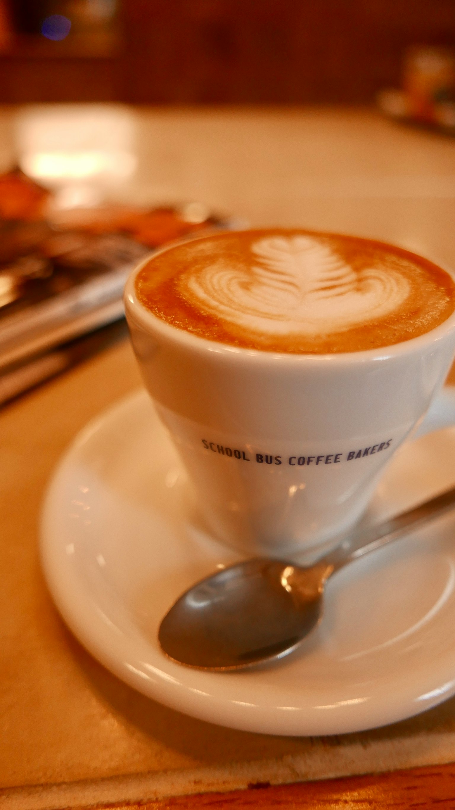 Caffè con arte del latte in una tazza bianca su un piattino