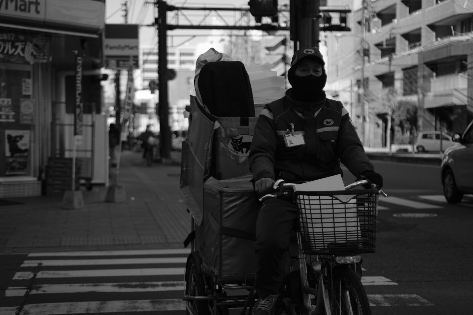 黑白照片，送貨員騎自行車穿過街道