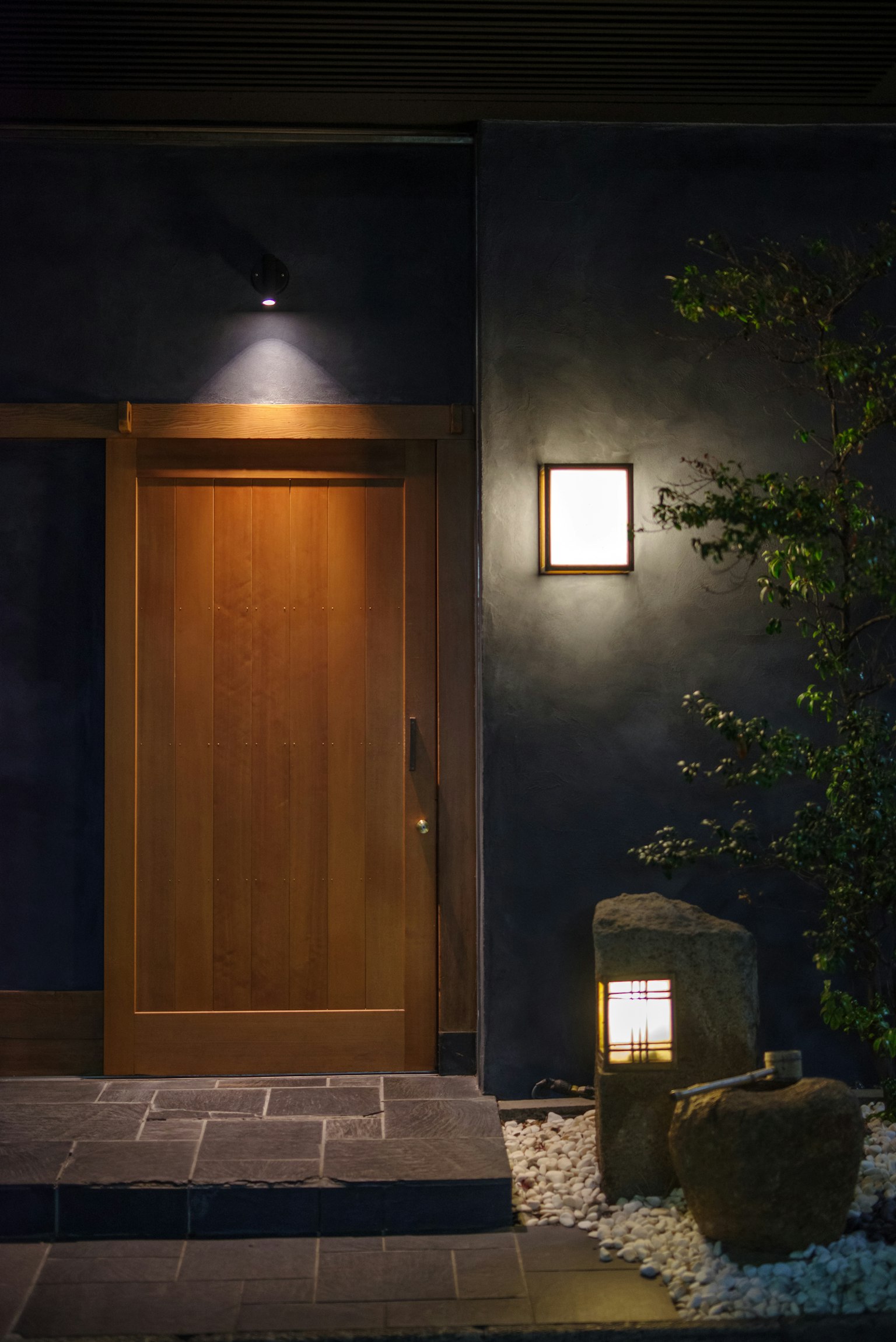 Entrada moderna con puerta de madera y luz ambiental