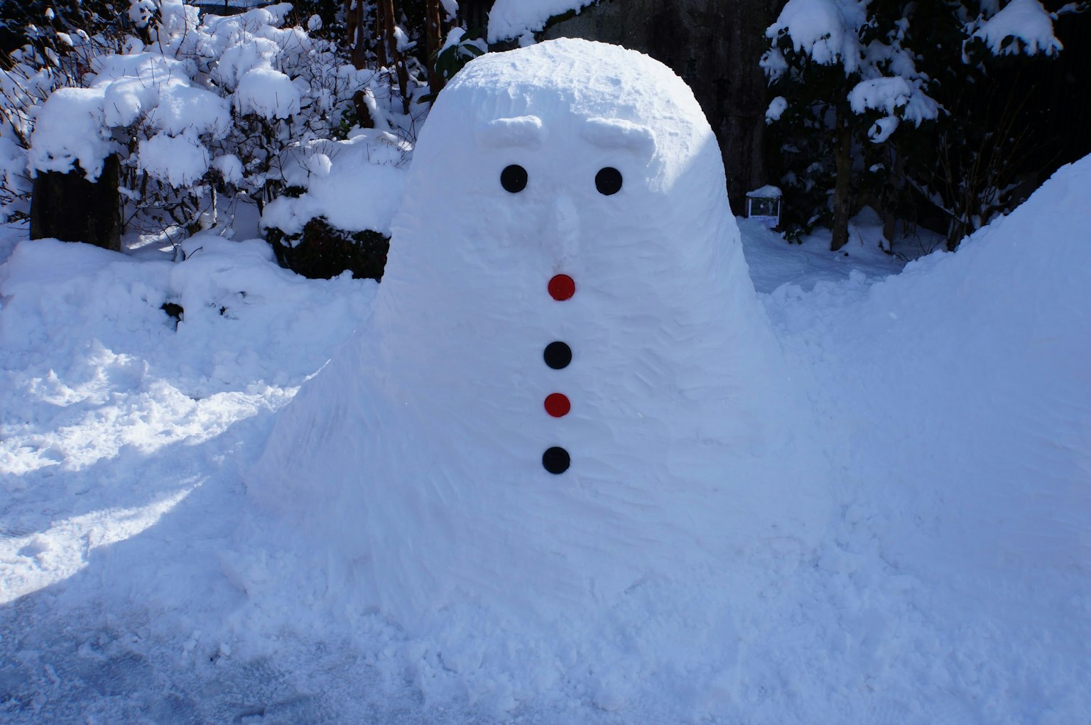 Snowman made of snow with red and black buttons