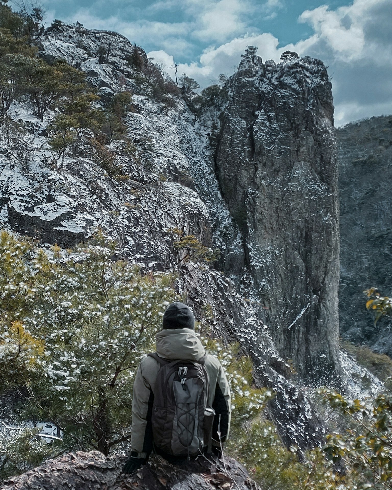 Hiker overlooking a rocky mountain with a blue sky