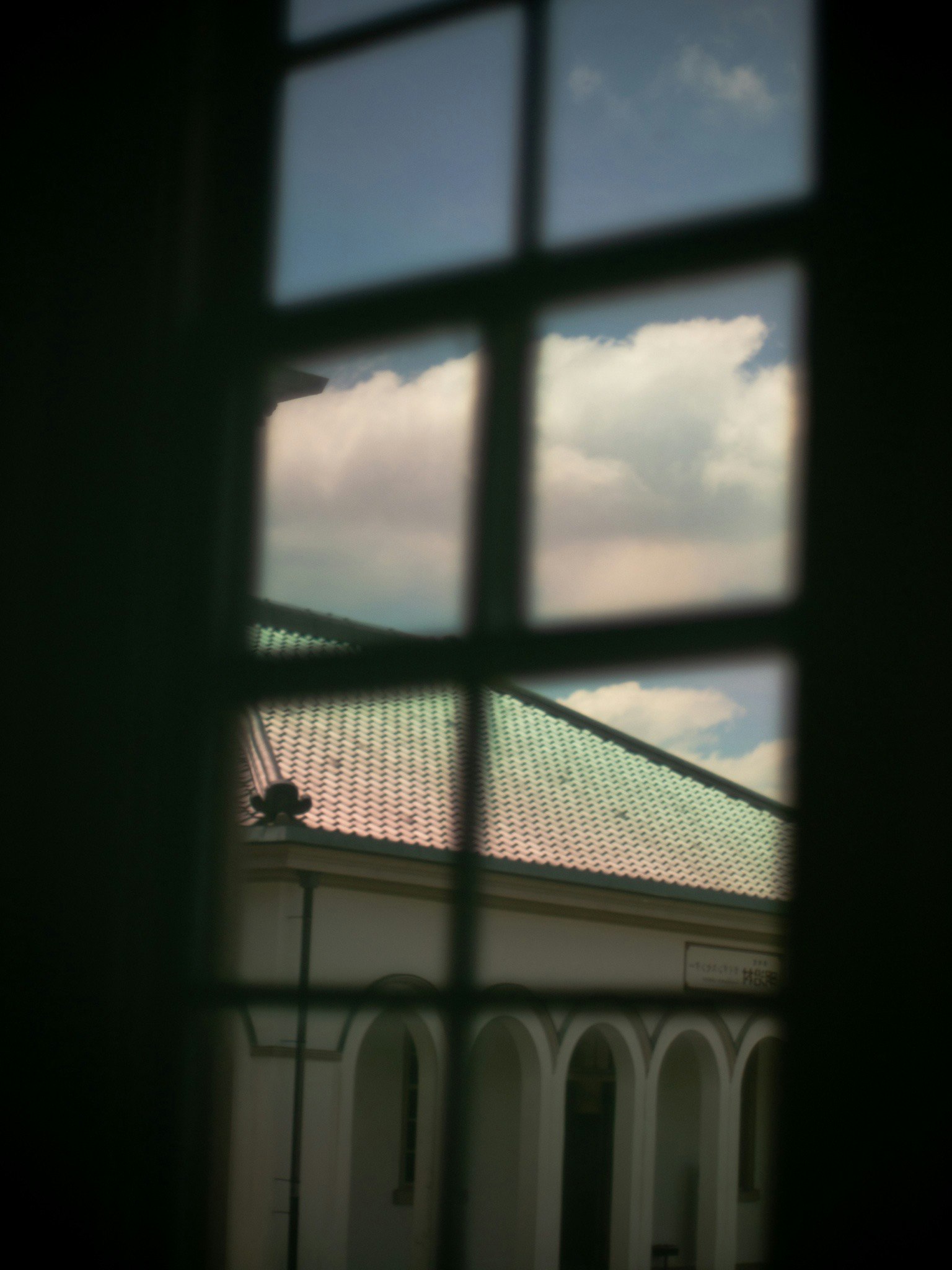 View of a roof and clouds through a window