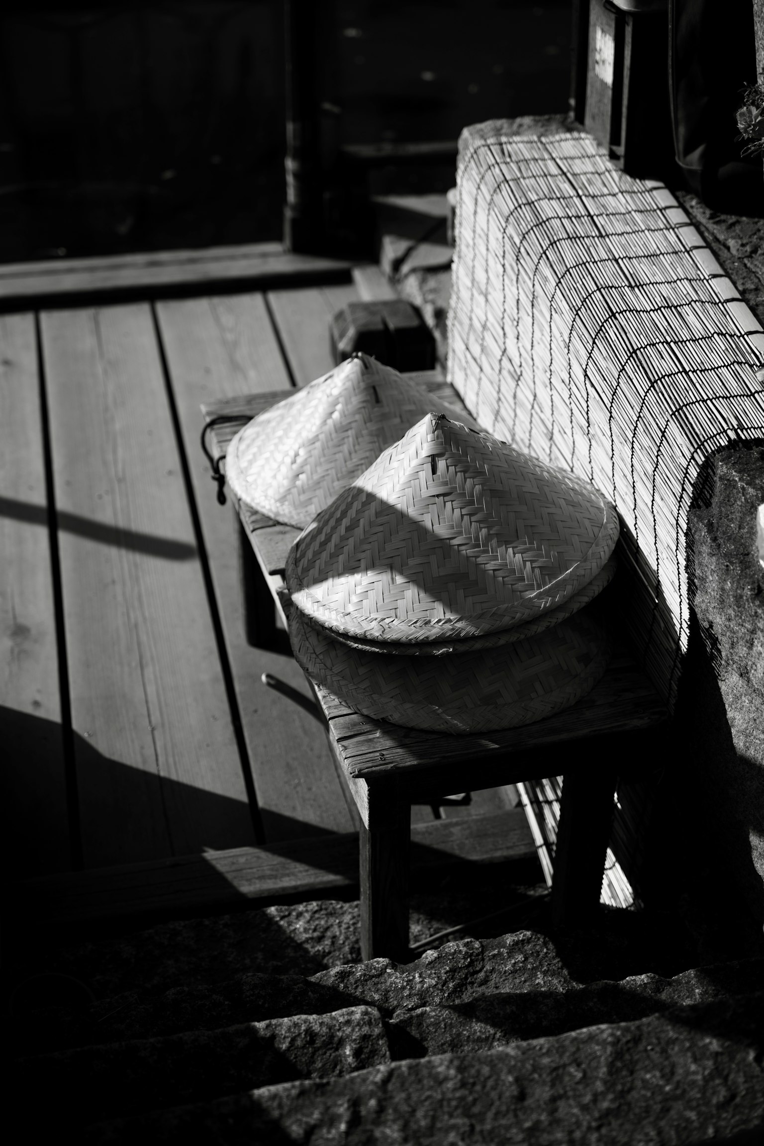 Two Asian-style hats on a wooden table with a checkered cloth