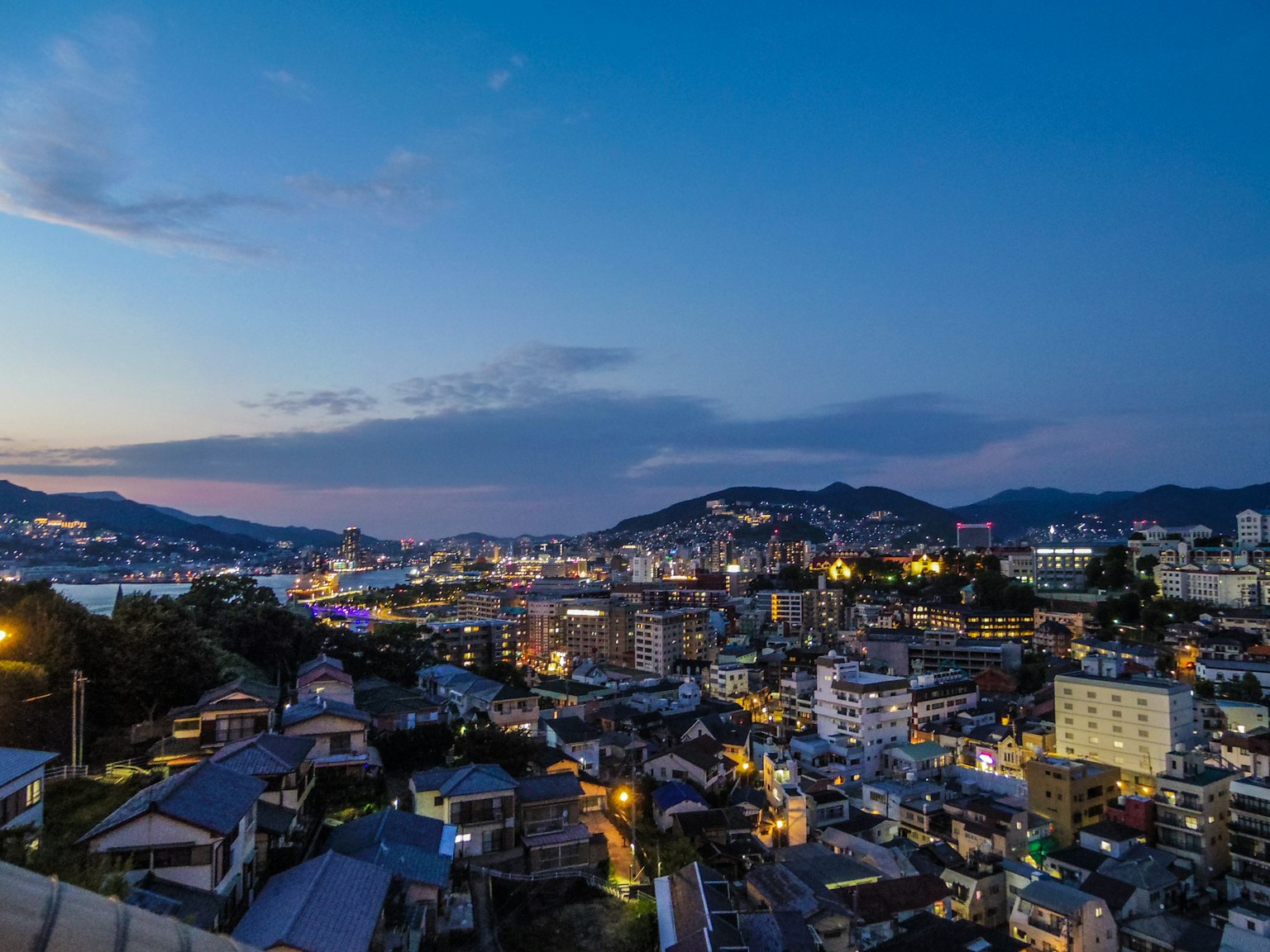 Night view of a city with buildings and mountains in the background
