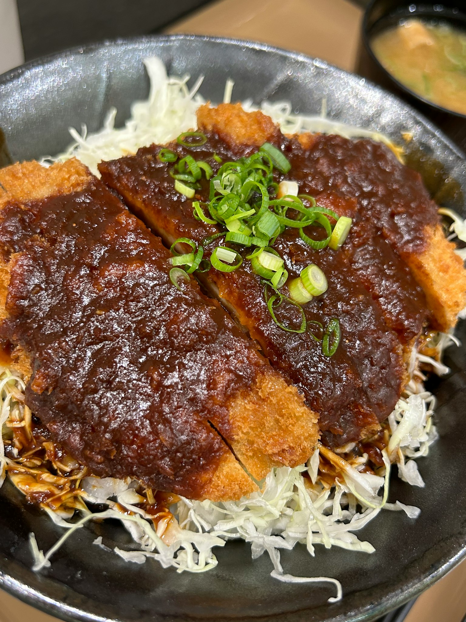 菜肴包括猪排，顶部有甜咸酱和青葱