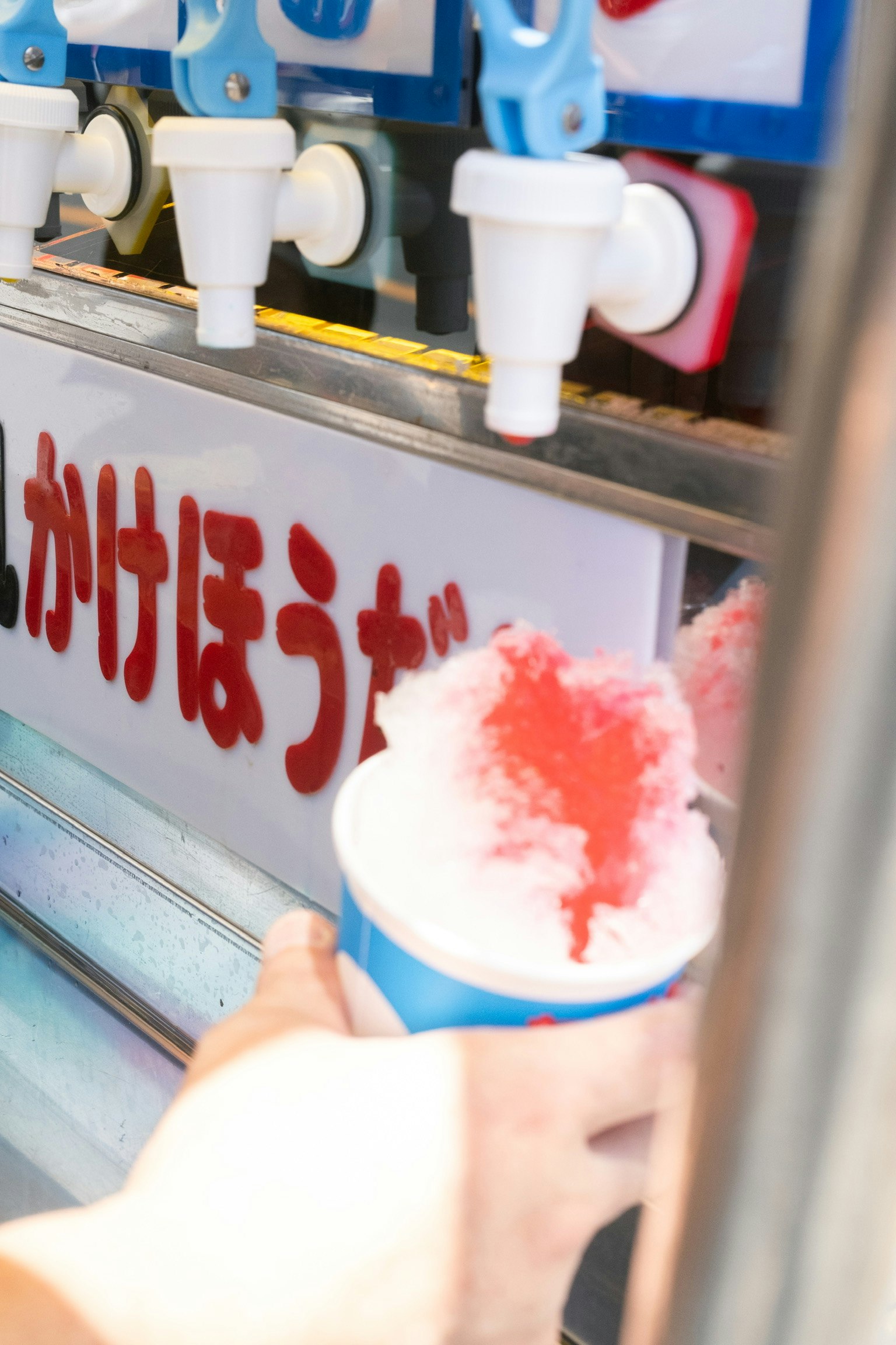かき氷シロップをかける手元の夏祭り屋台の画像