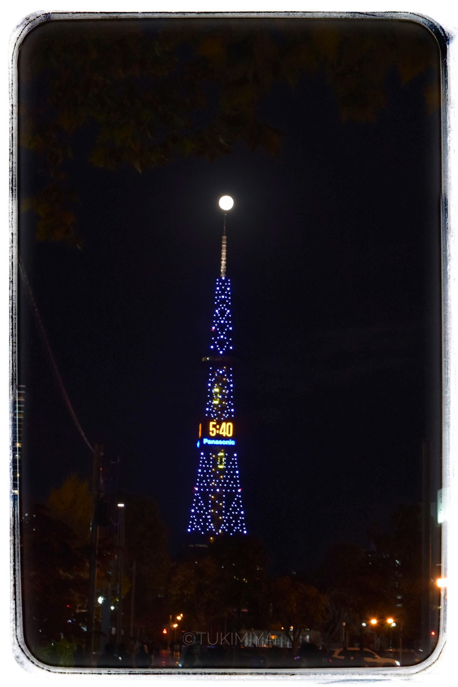 夜の東京タワーが青いライトで装飾されている月明かりの下