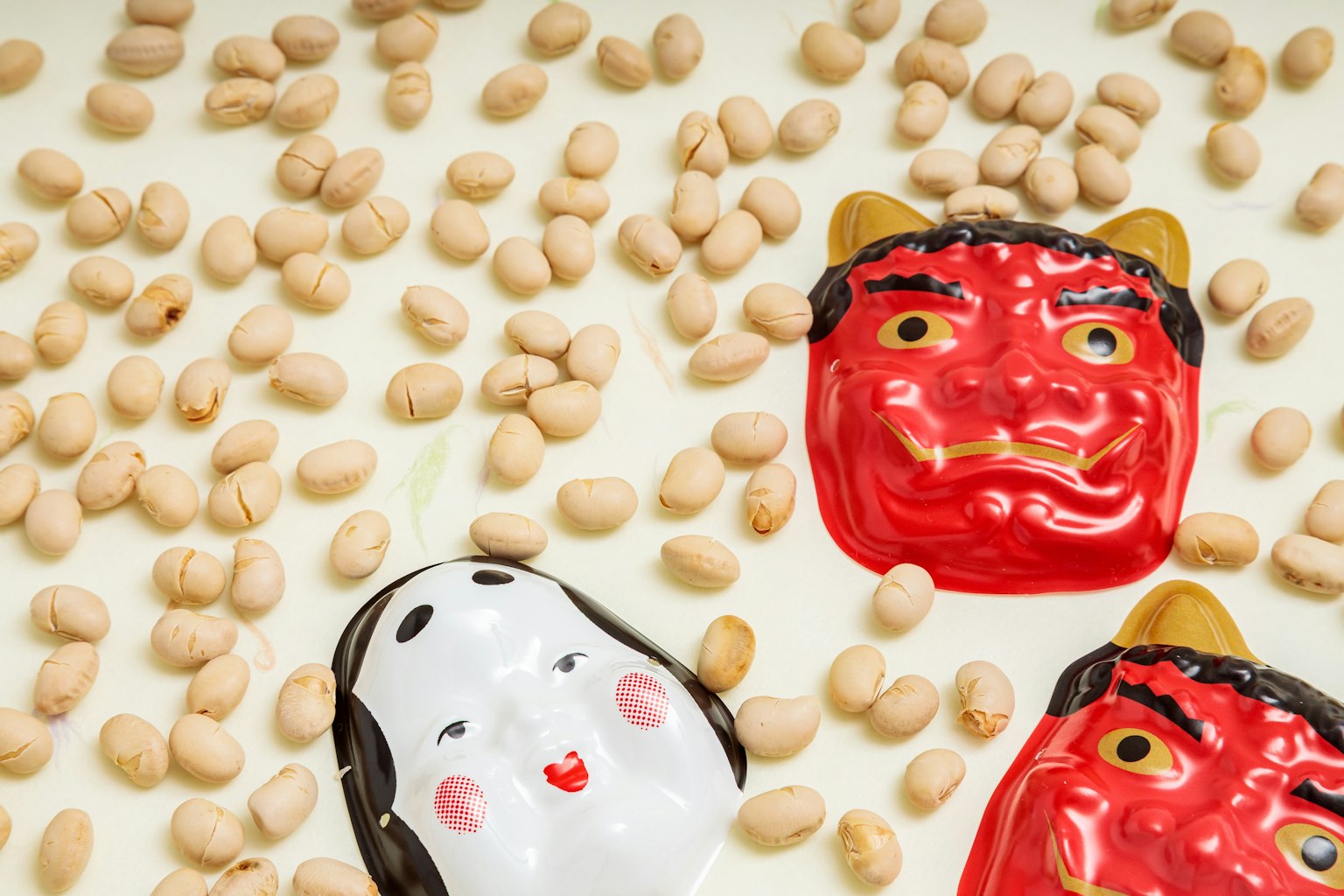 赤い鬼と白い鬼のマスクが豆の上に置かれている