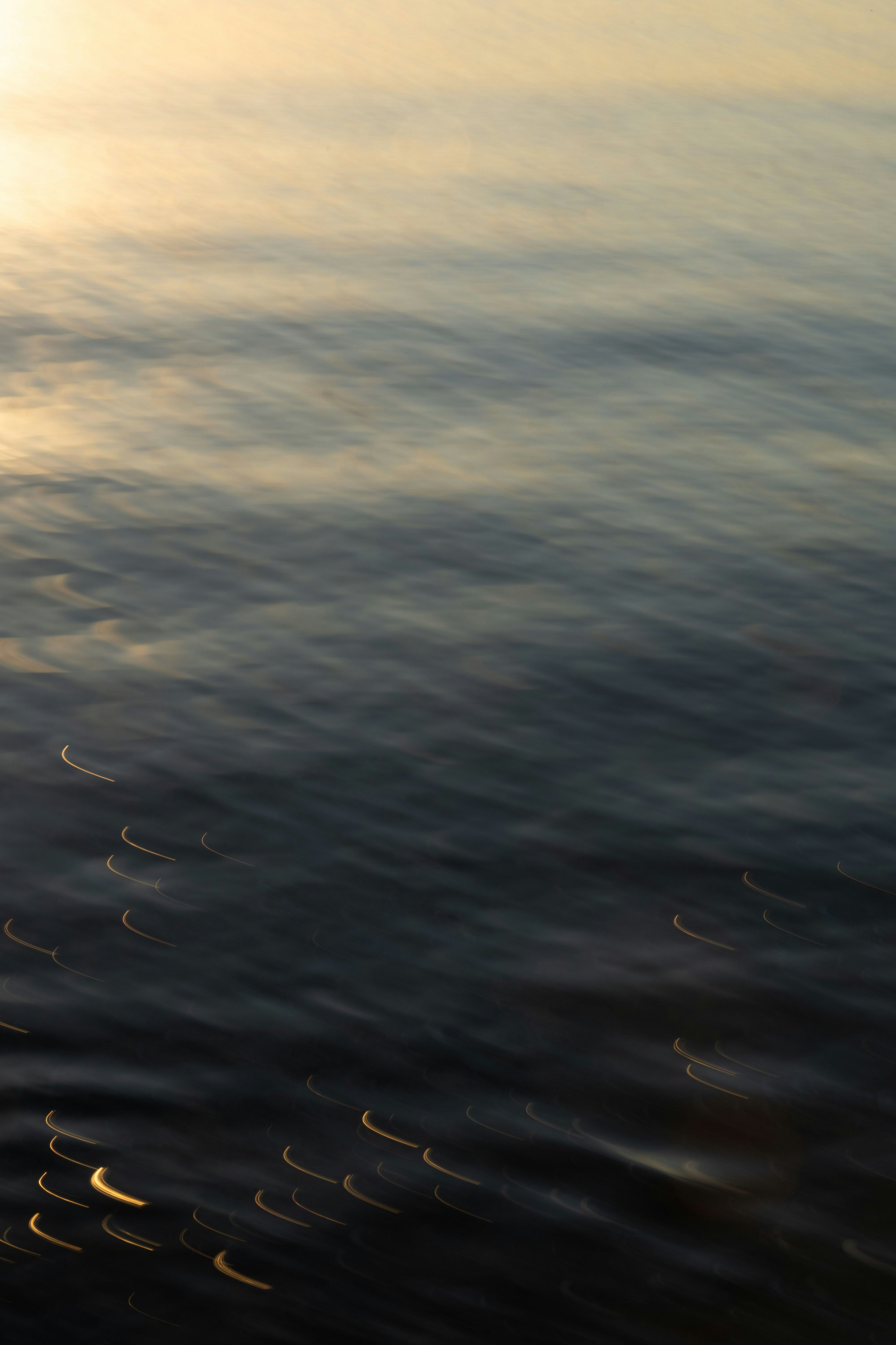 夕暮れの海面に浮かぶ波と光の筋