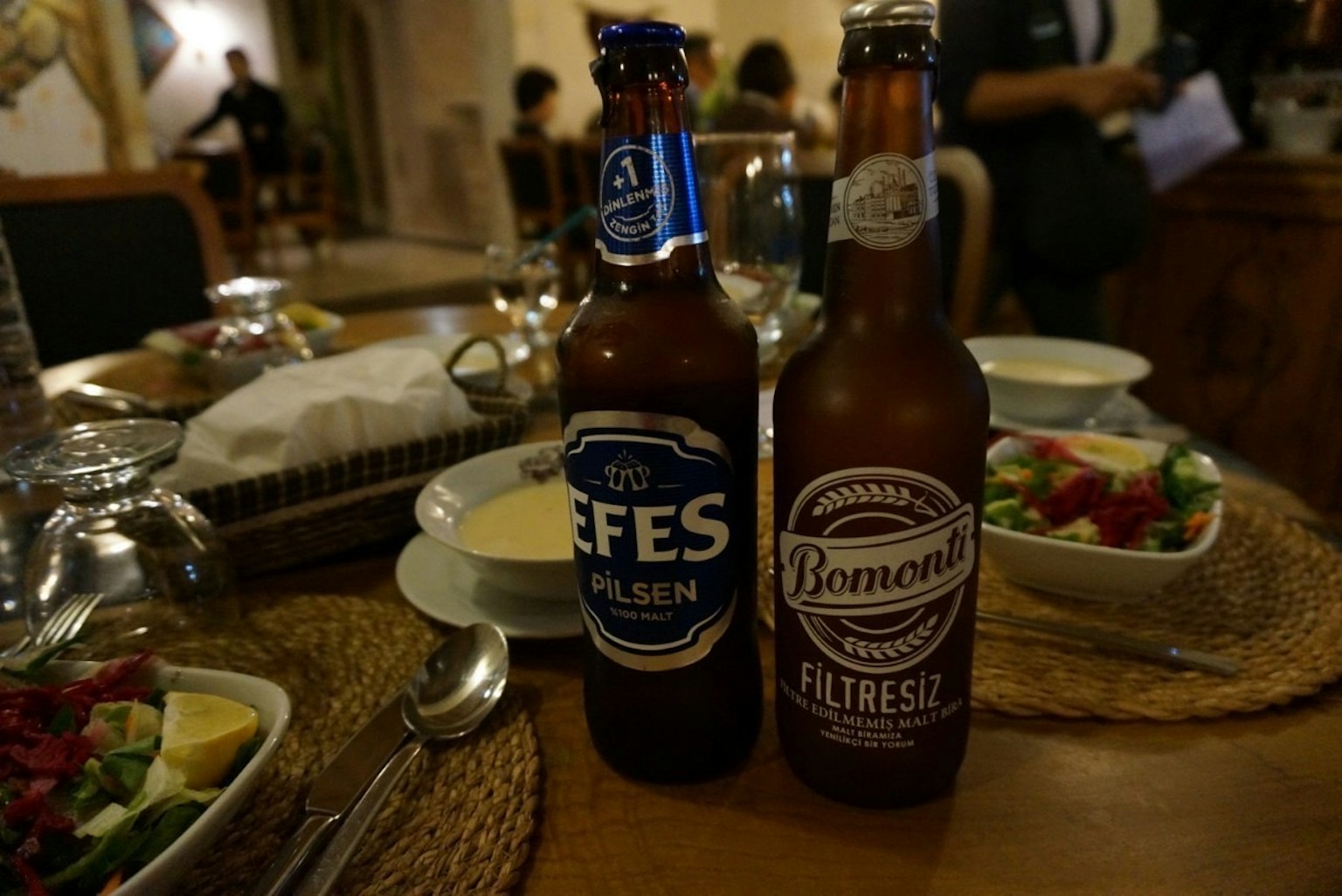Dua botol bir Efes dan Bomonti di atas meja makan