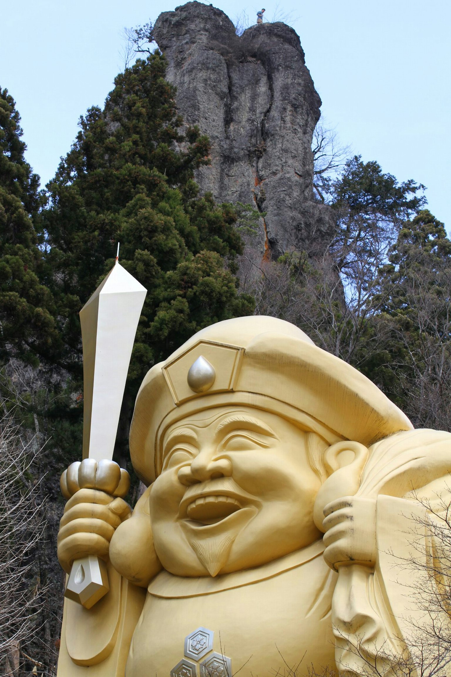 Large golden deity statue holding a sword with mountains in the background