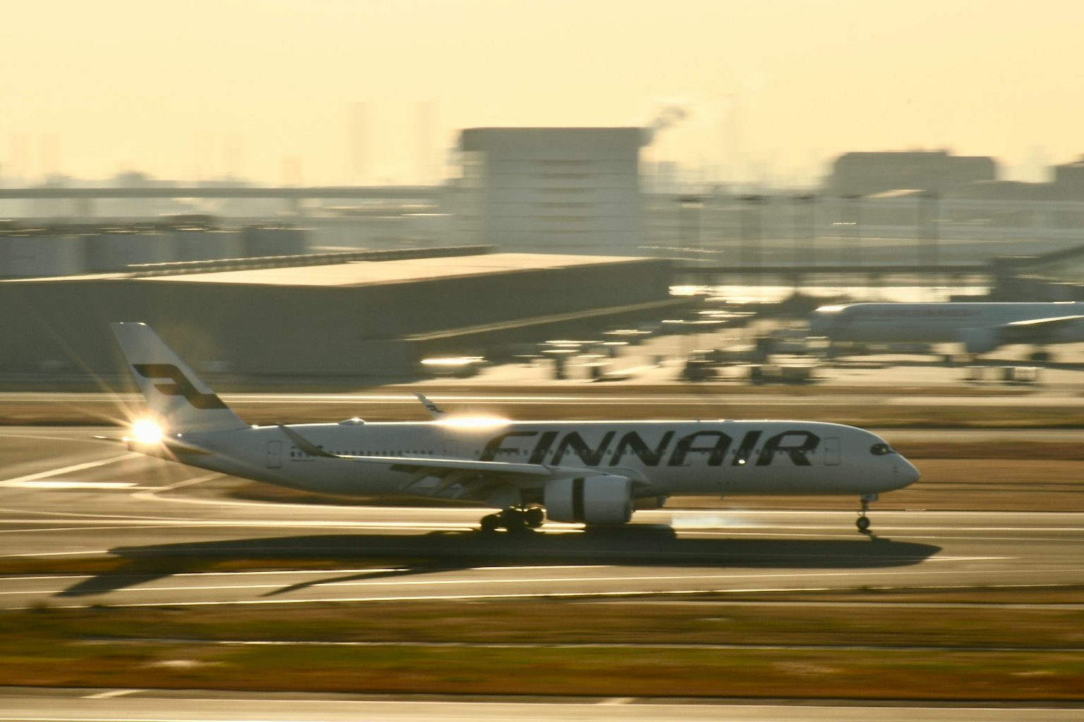 เครื่องบินโดยสาร Finnair กำลังวิ่งบนรันเวย์กับพื้นหลังพระอาทิตย์ตก