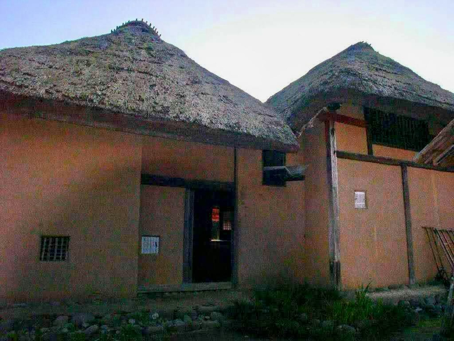 Pemandangan luar rumah tradisional dengan atap ilalang