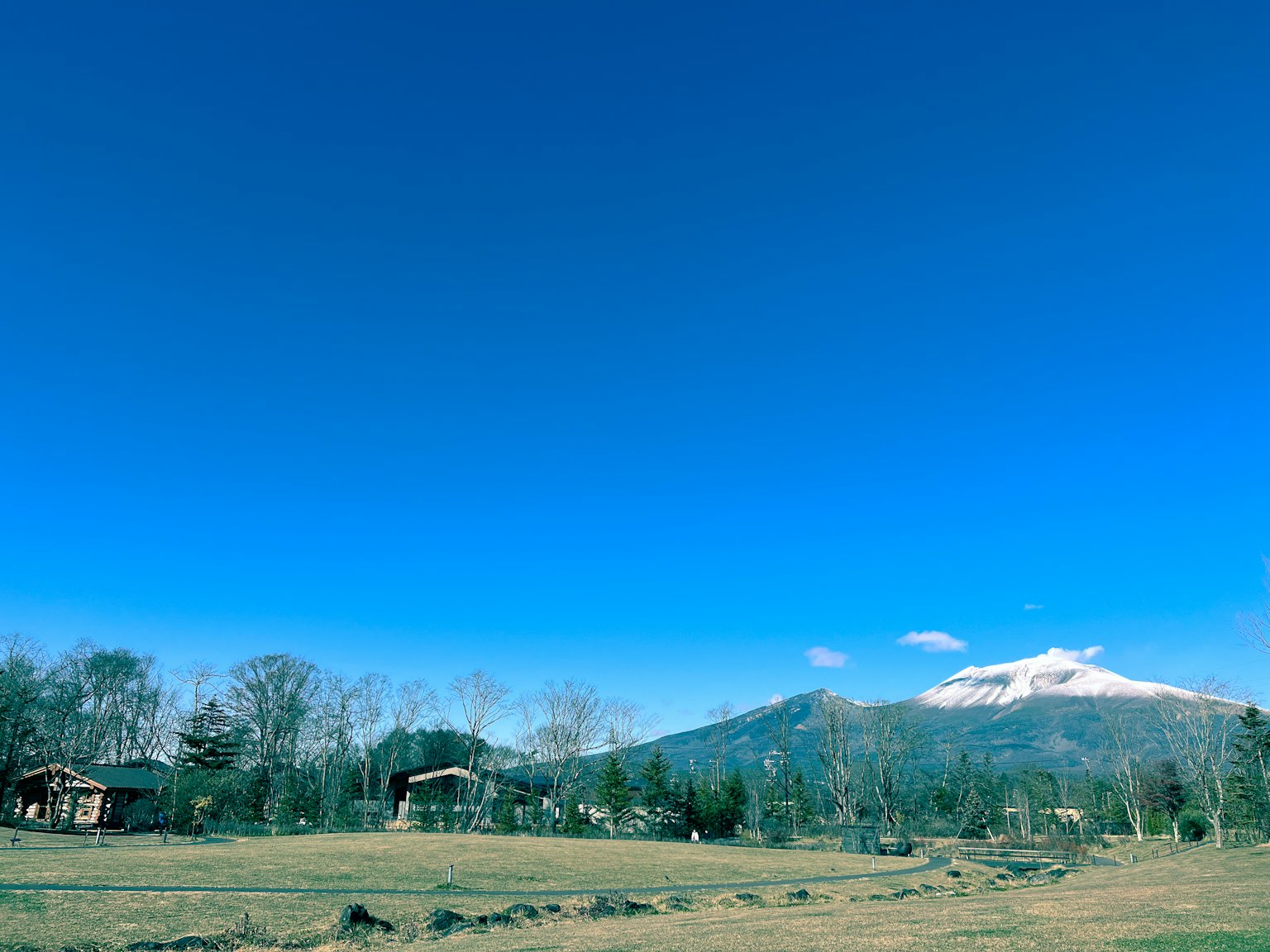 Pemandangan langit biru cerah dengan gunung bersalju beberapa kabin dan pohon di sekitarnya
