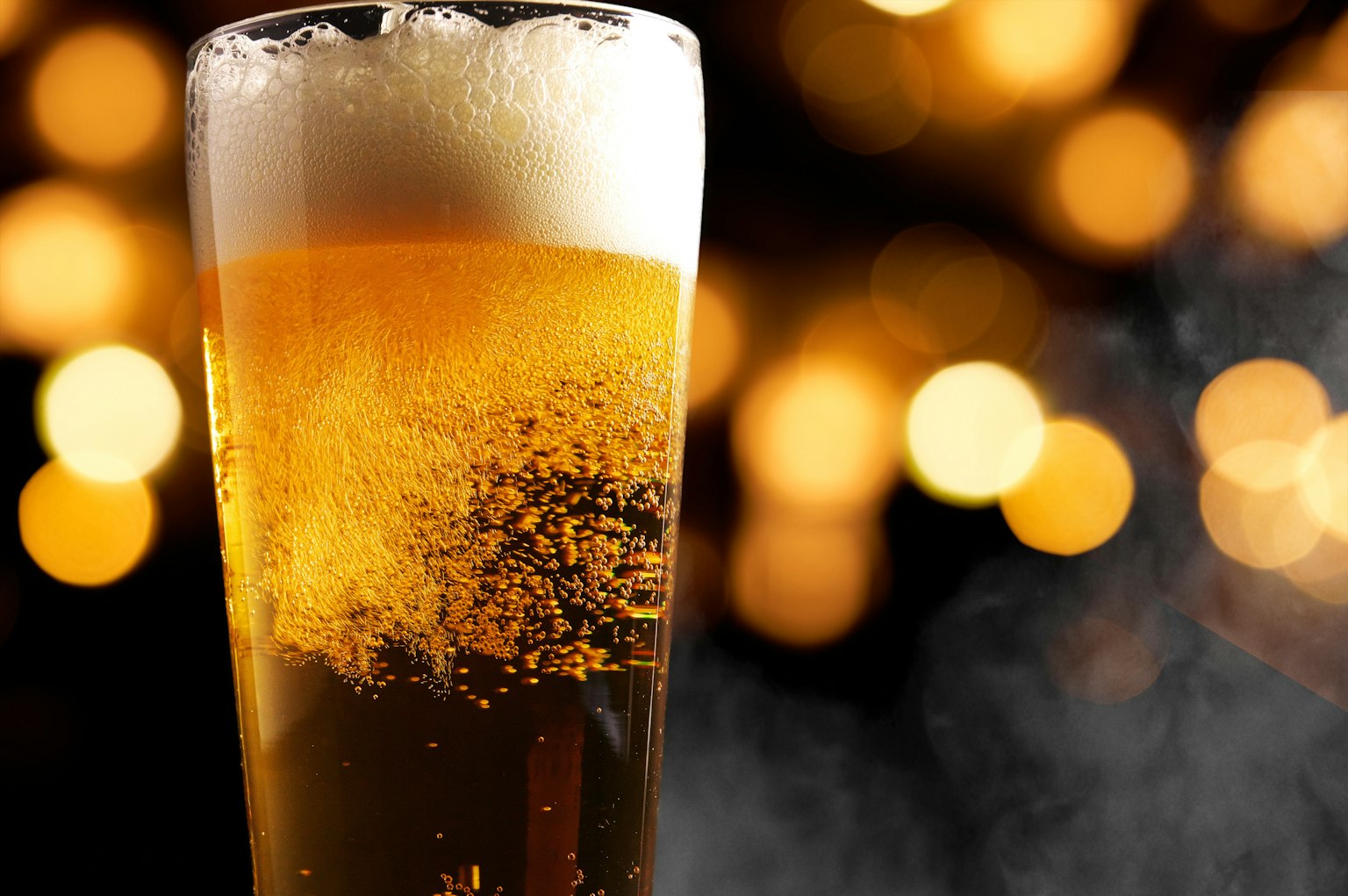 Un bicchiere di birra schiumosa con uno sfondo luminoso sfocato