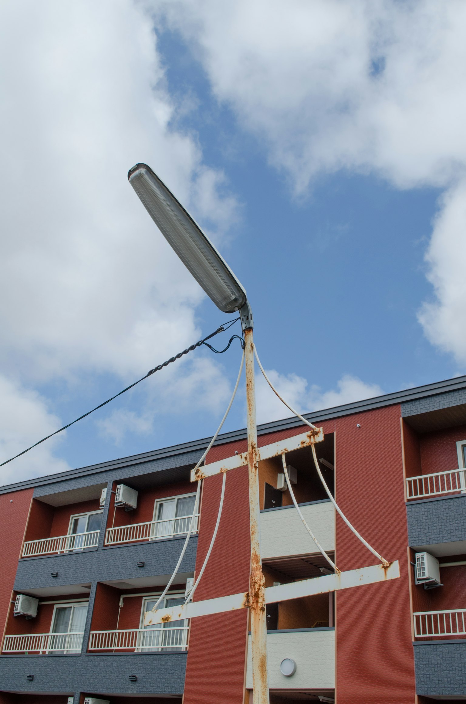 Alter Straßenlaterne unter blauem Himmel mit rotem Wohngebäude