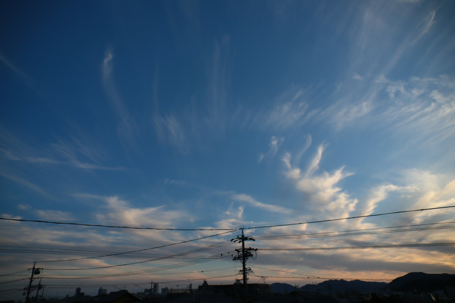 Blauer Himmel mit dünnen Wolken und Bergsilhouette