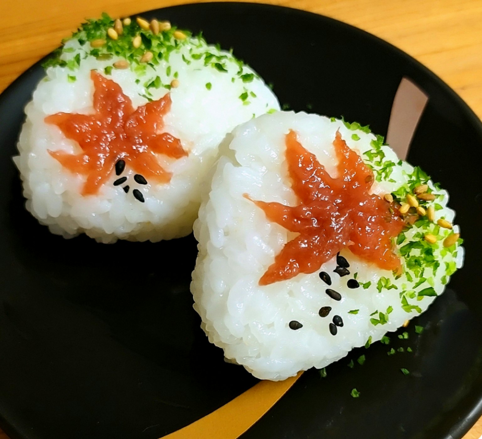 黑色盘子上的两个秋叶形状的饭团