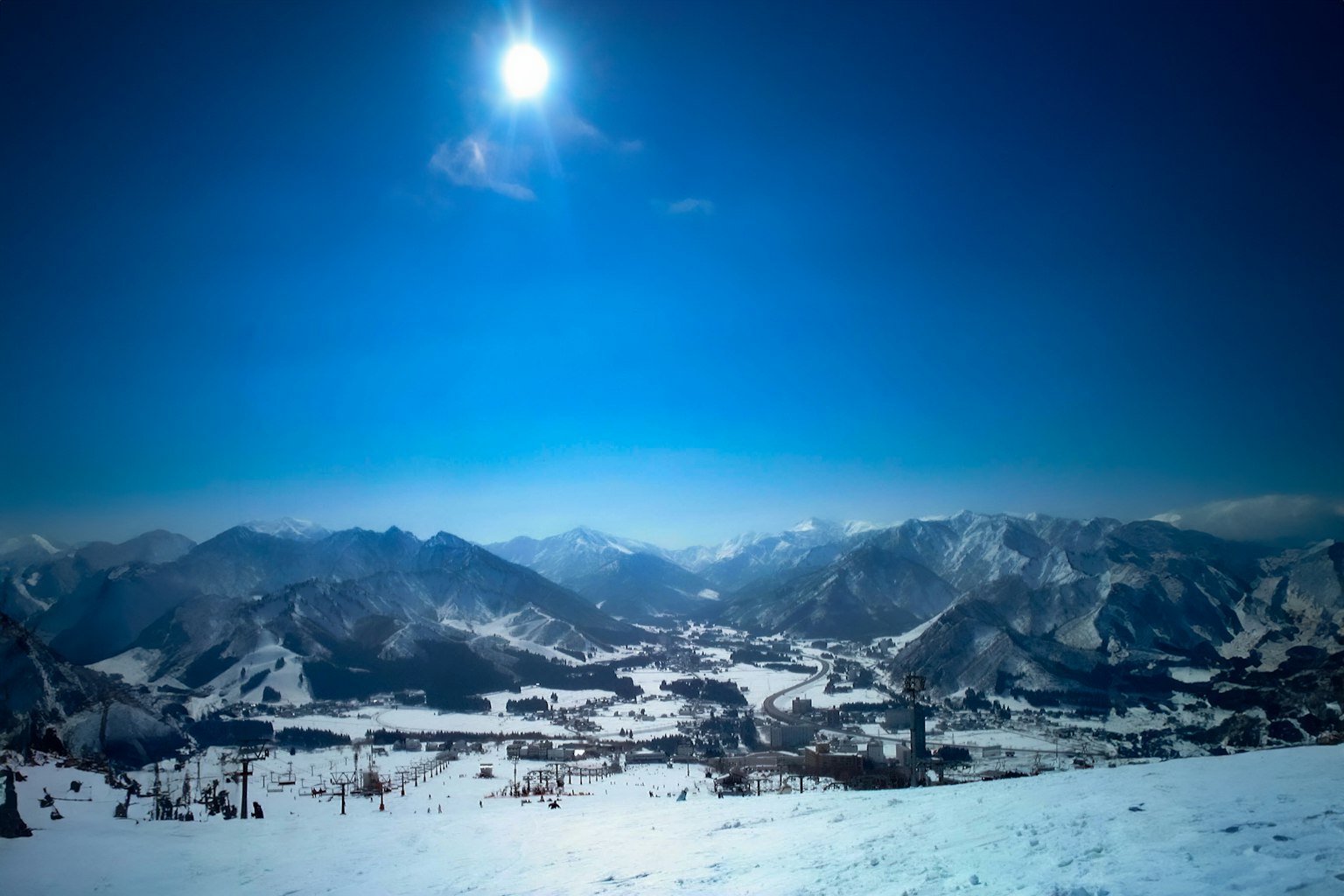 Vue panoramique des montagnes couvertes de neige sous un ciel bleu avec un soleil brillant