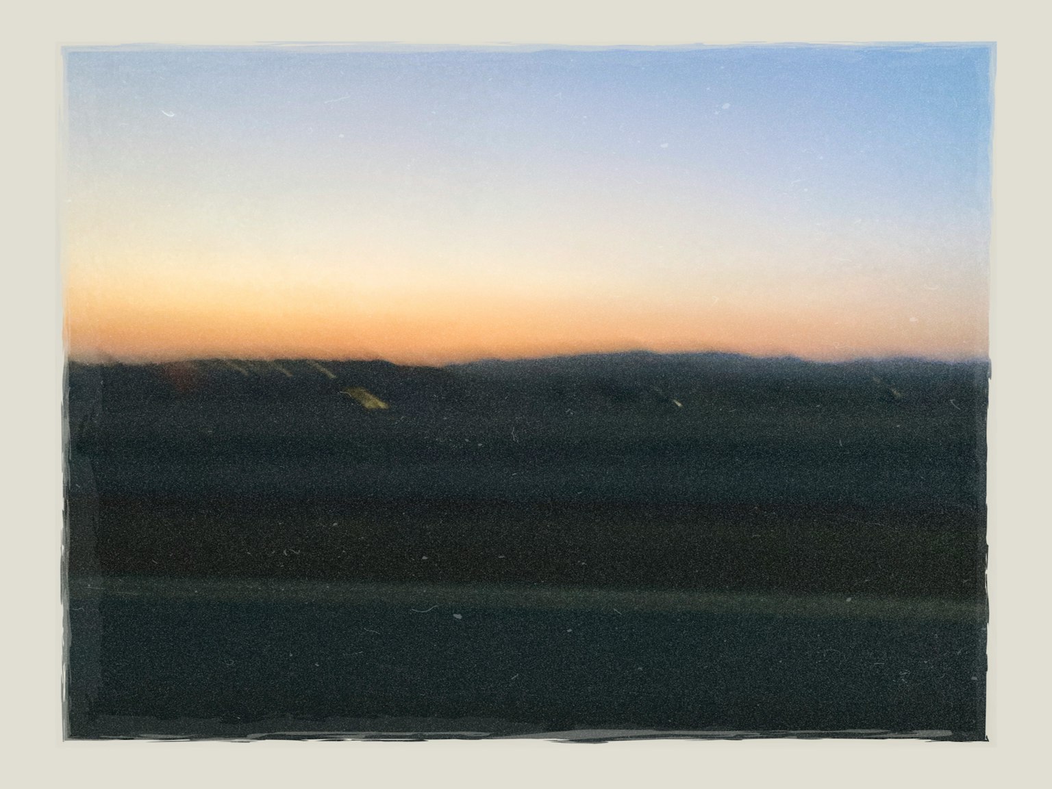 Eine schöne Sonnenuntergangslandschaft mit Silhouetten niedriger Hügel und sanften Farben im Himmel
