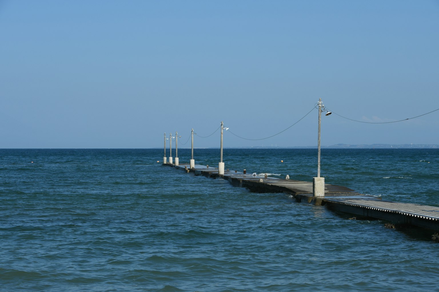 Steg, der ins blaue Meer unter einem klaren Himmel führt