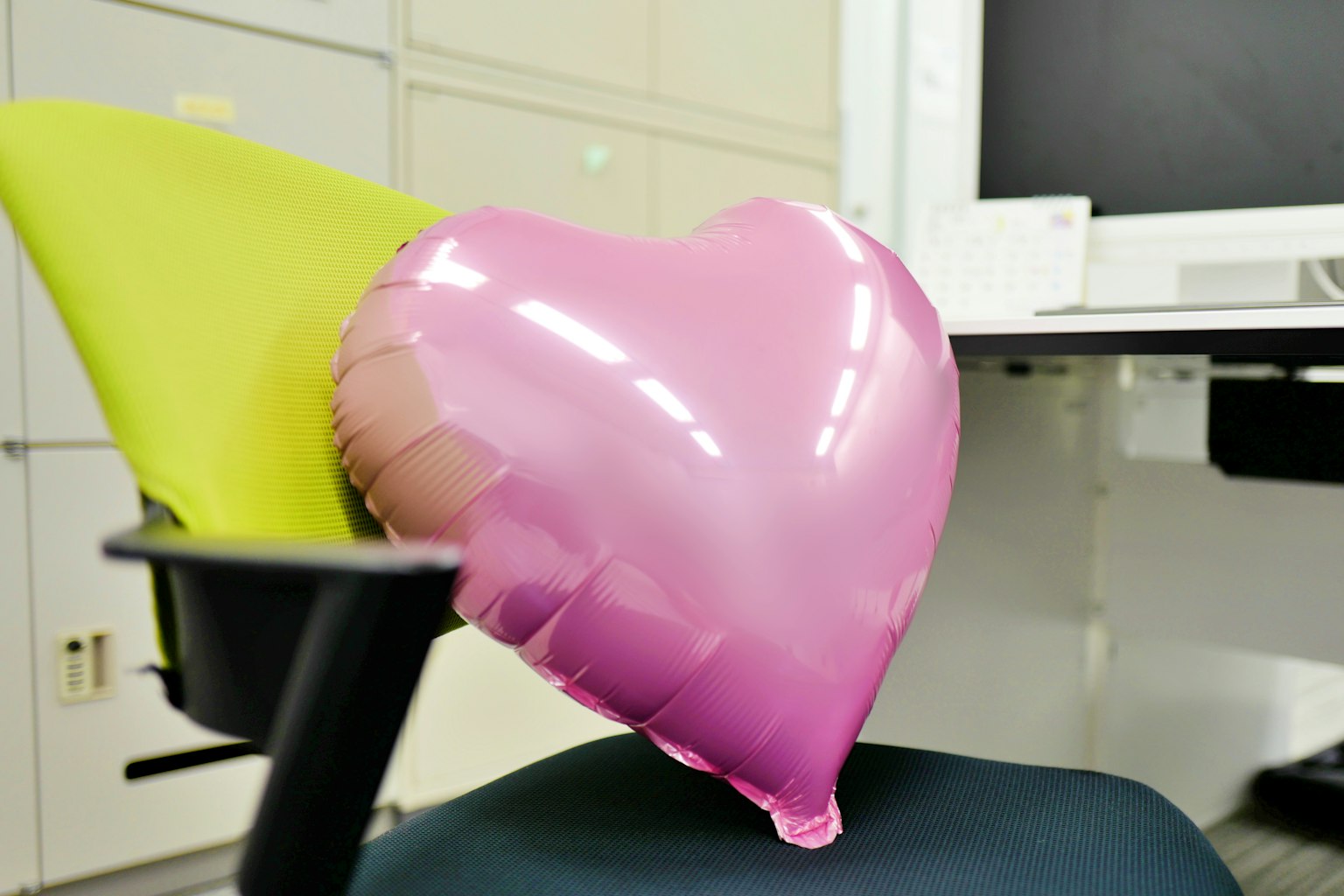 Palloncino rosa a forma di cuore appoggiato su una sedia