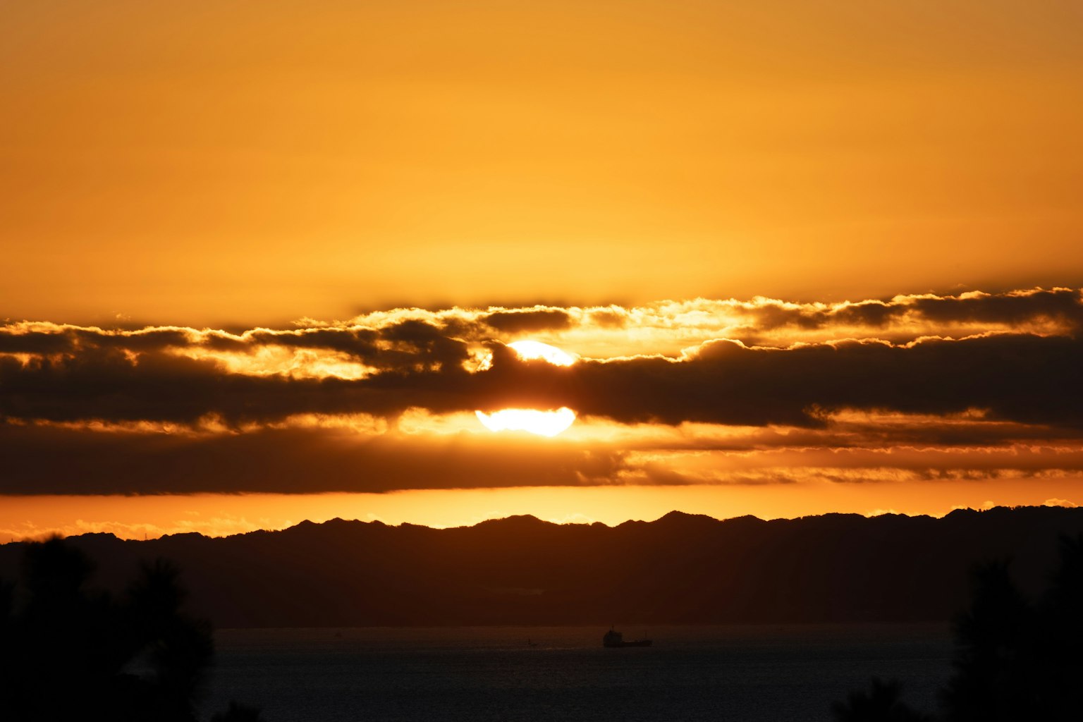 Coucher de soleil magnifique avec le soleil se couchant derrière des nuages et des montagnes