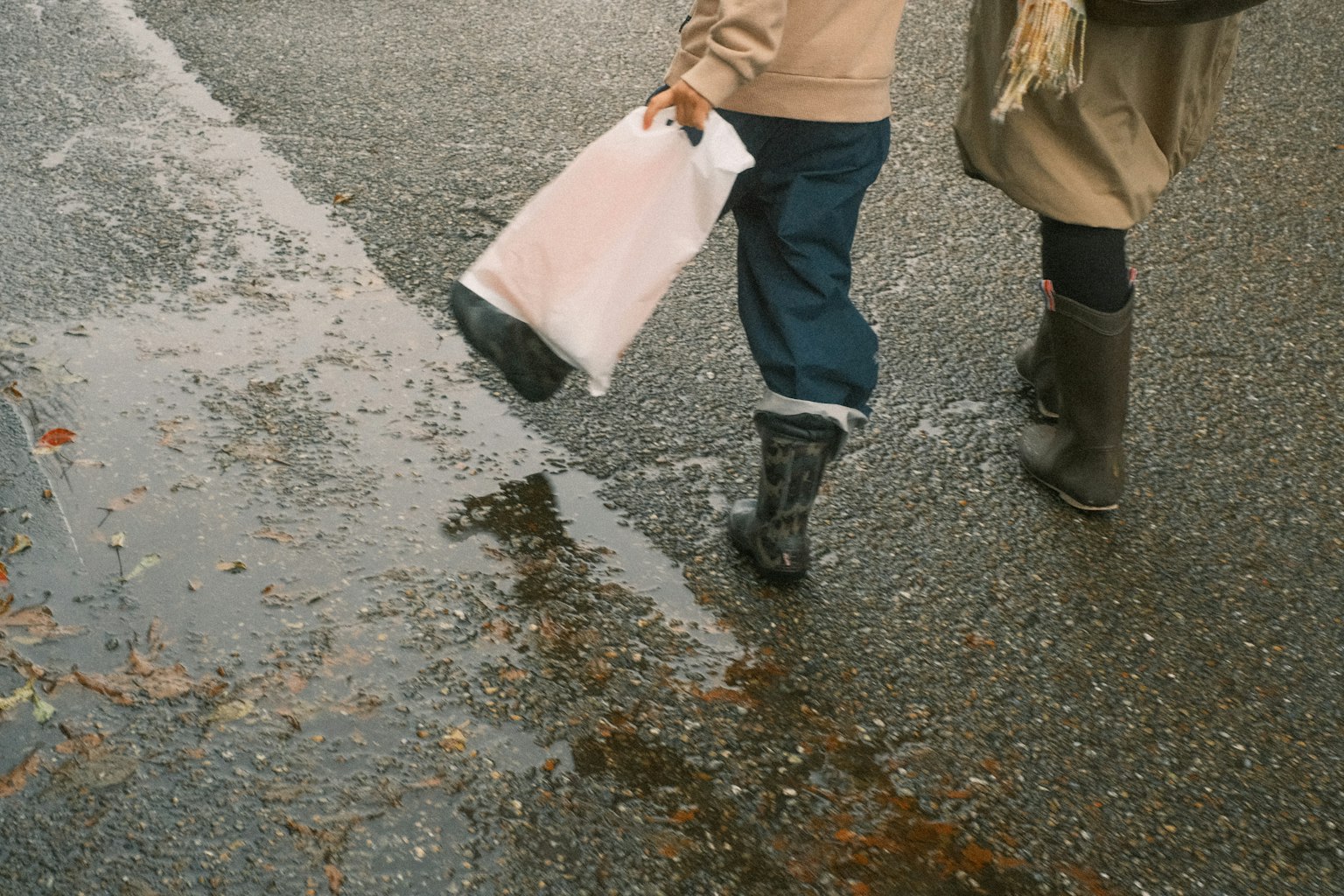 Deux personnes marchant sous la pluie avec des flaques d'eau au sol