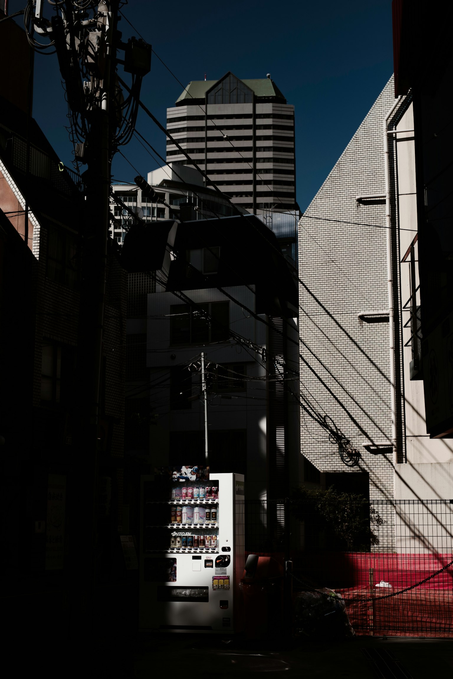 Dark alley with a vending machine and shadows of a skyscraper